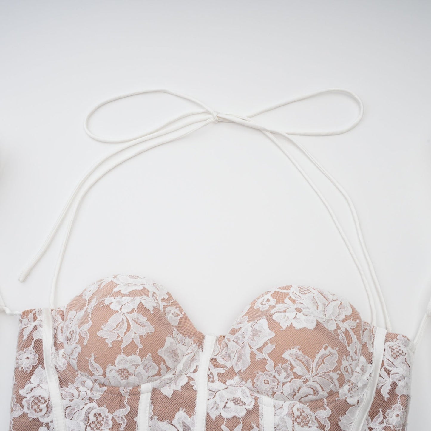 A white mini dress with floral lace pattern featuring a corset style bodice and short skirt