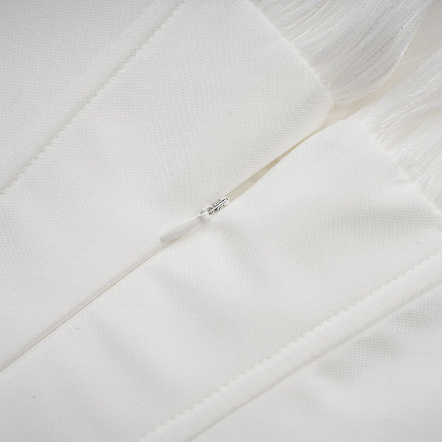 A white mini dress with full pleating and a cinched waist featuring a rosier design