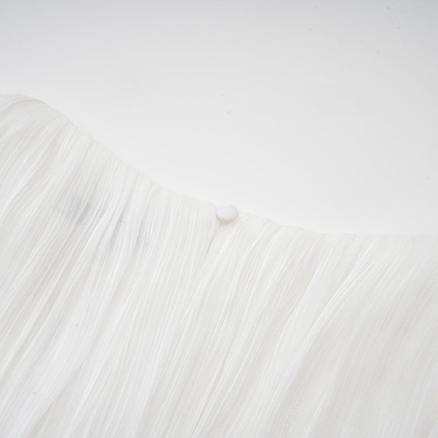 A white mini dress with full pleats and a cinched waist detail featuring a rosier design
