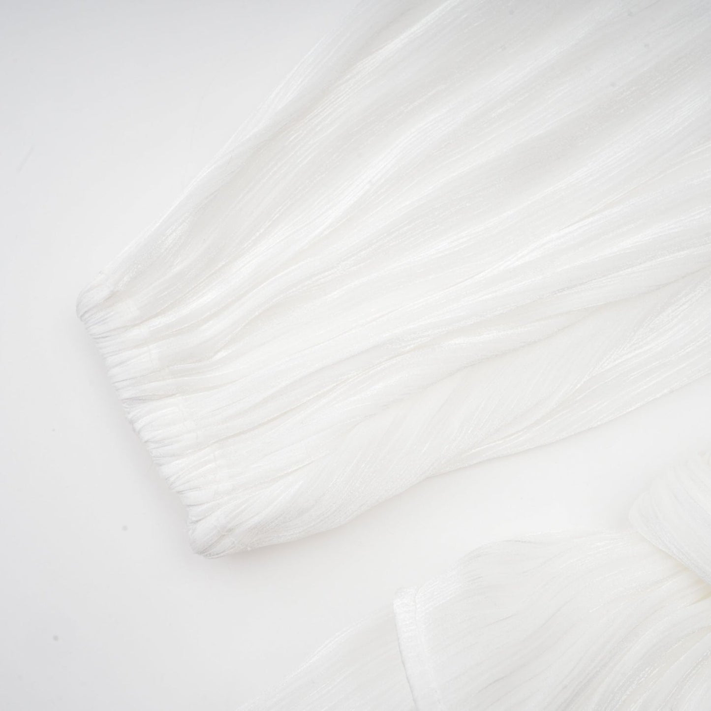 A white mini dress with full pleats and a cinched waist featuring a rosier design