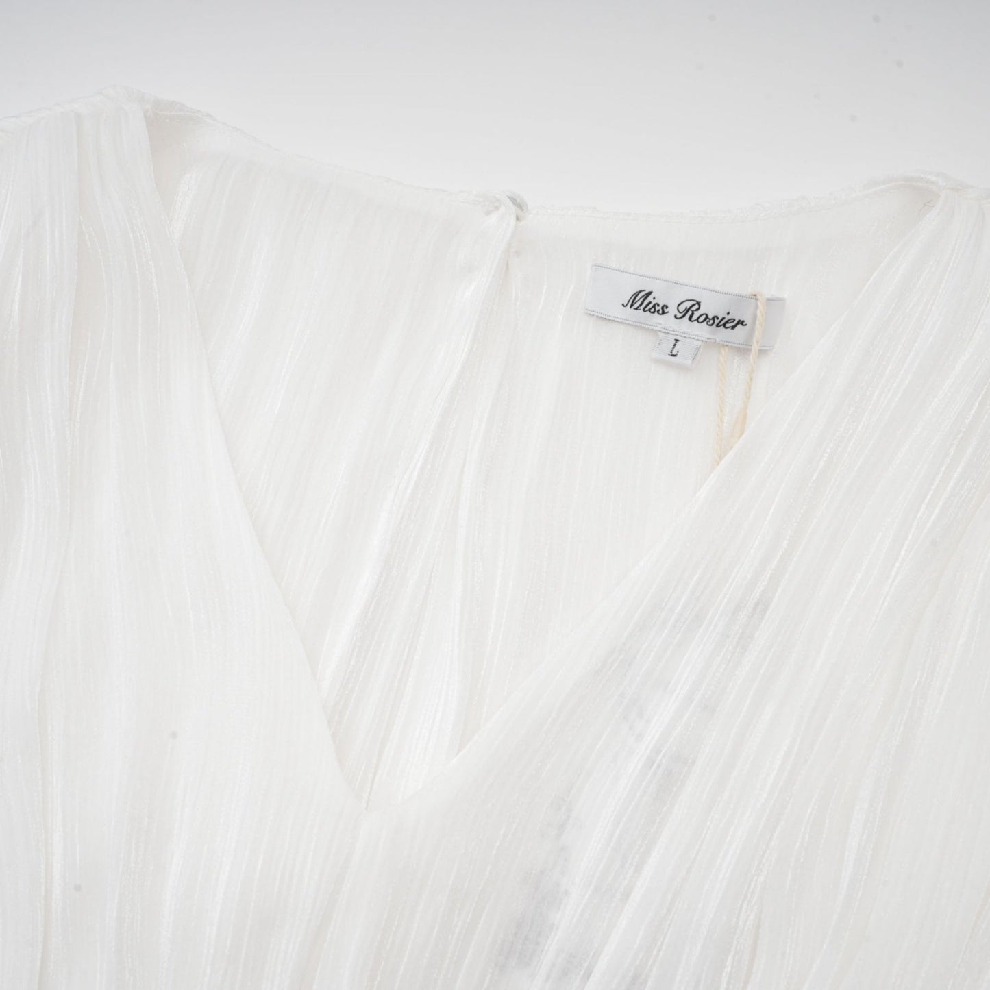 A white mini dress with full pleats and a cinched waist featuring a rosier design
