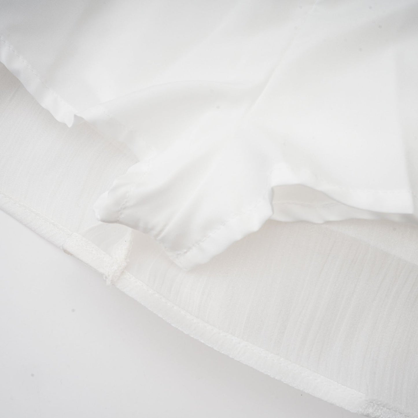 A white mini dress with full pleats and a cinched waist featuring a rosier design