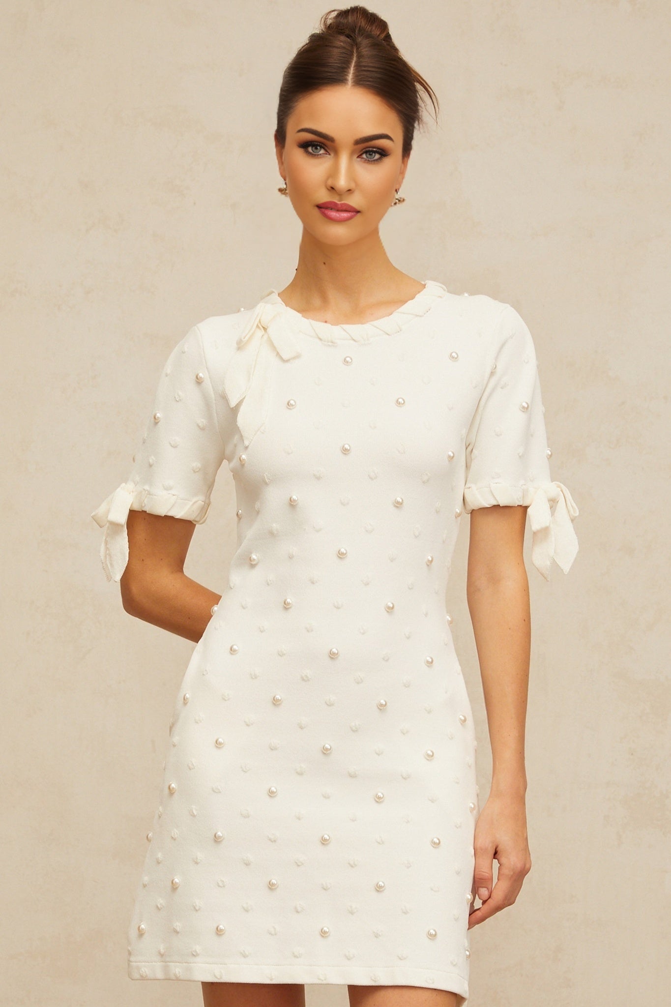 A white mini dress with polka dot pattern and heart design knitted into the fabric featuring a short hemline and Prunelle branding