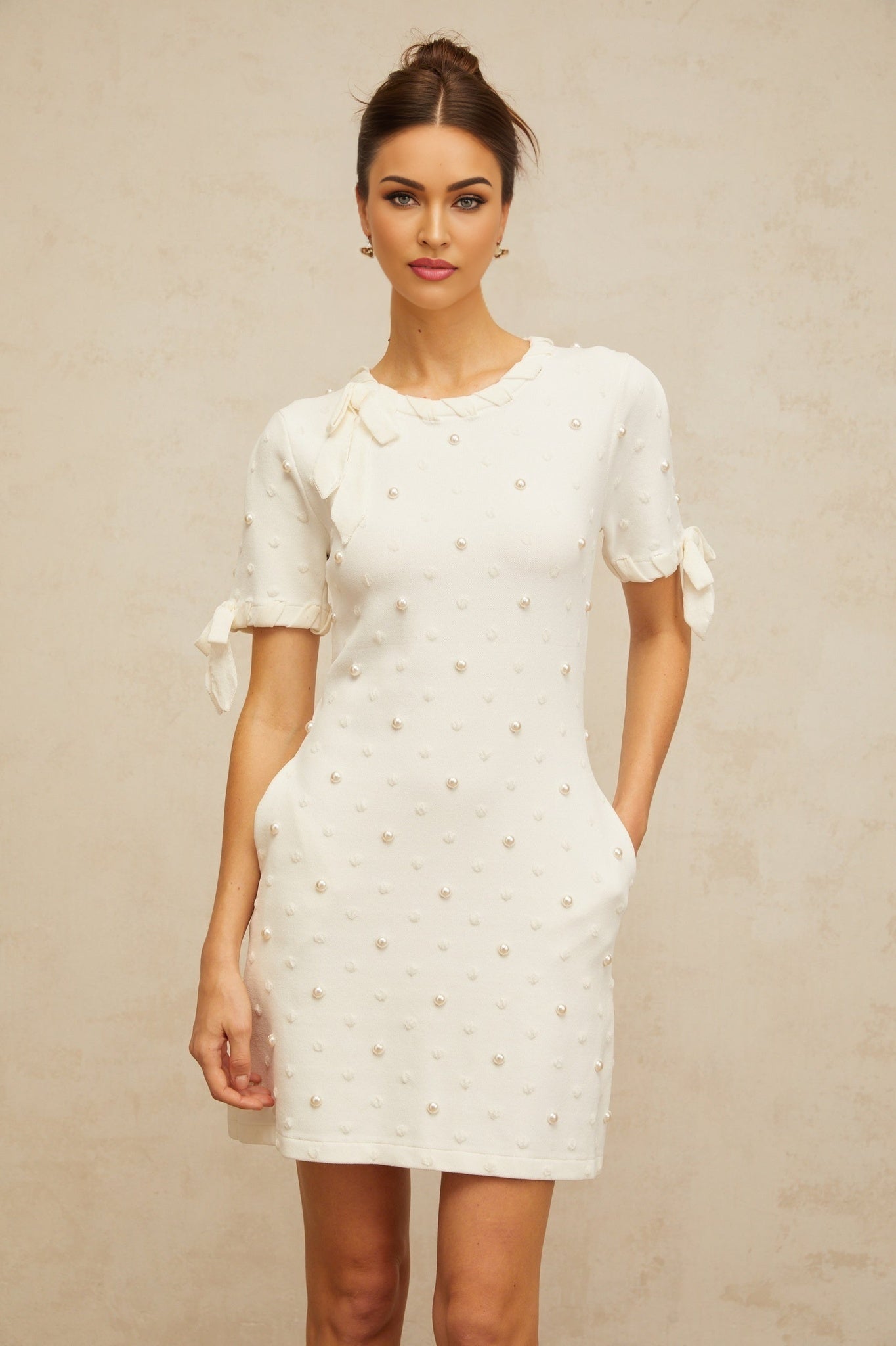 A white mini dress with polka dot pattern and heart designs knitted into the fabric featuring short sleeves and a fitted silhouette