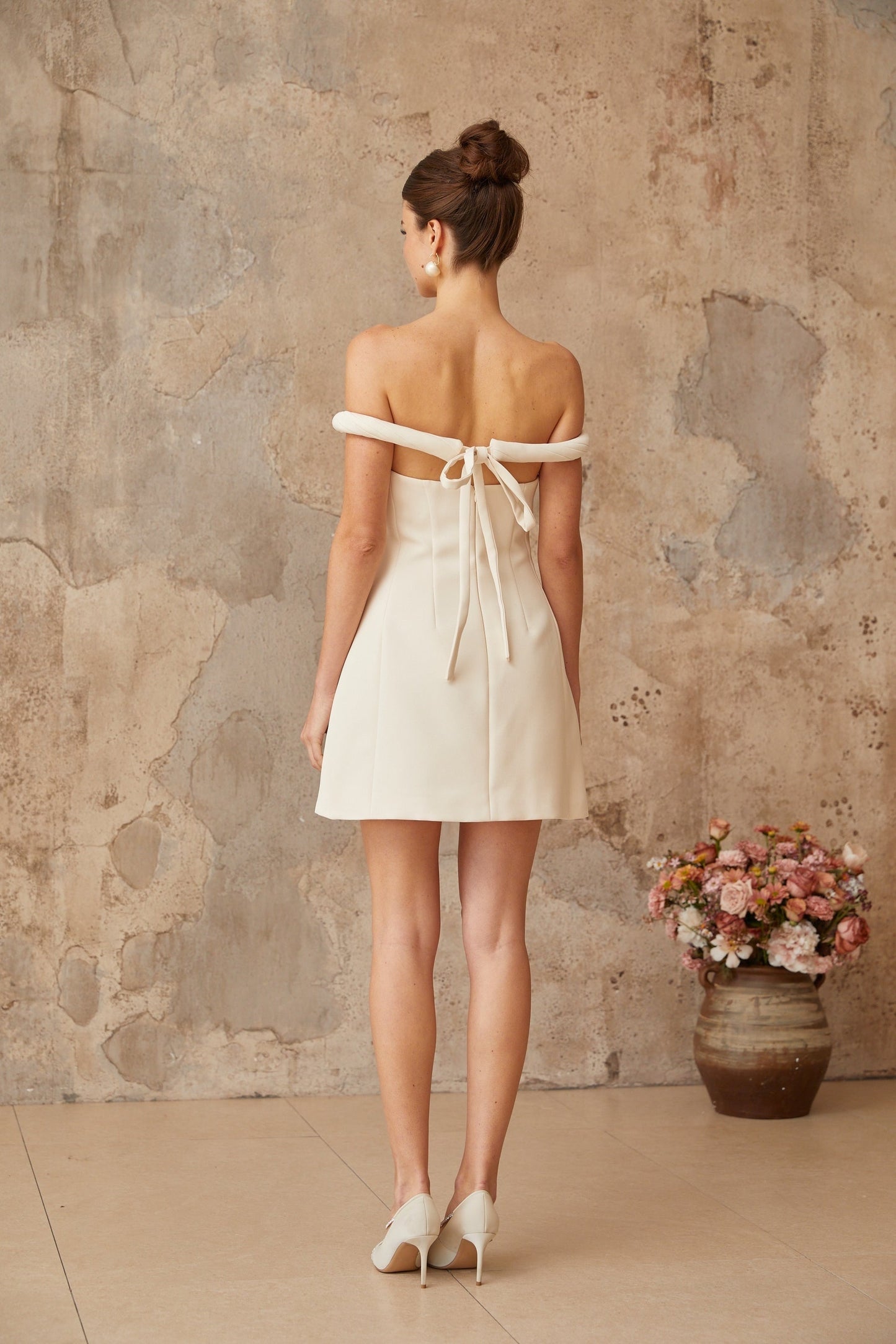 A white mini dress with puff sleeves and braided detailing featuring a short hemline and feminine silhouette