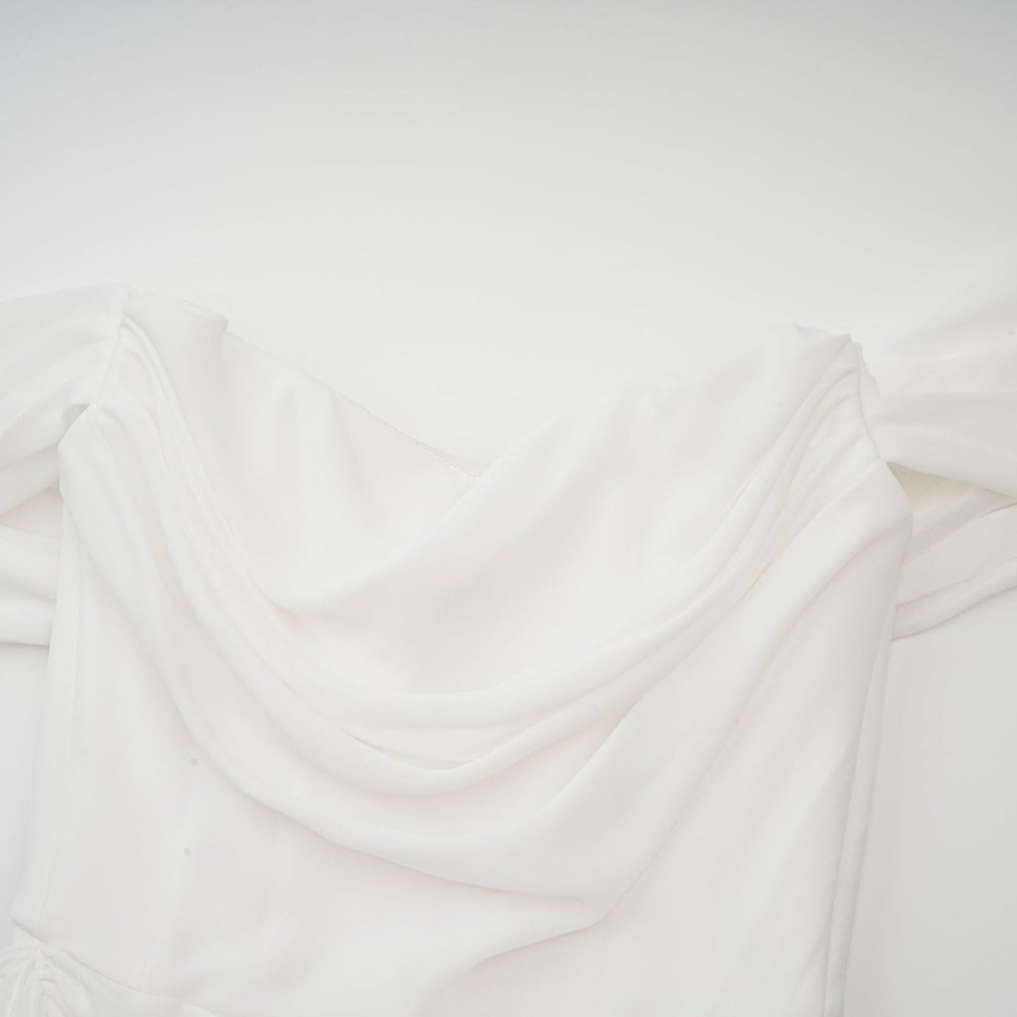 A white mini dress with ruched fabric and ribbon design details featuring a short hemline and formfitting silhouette