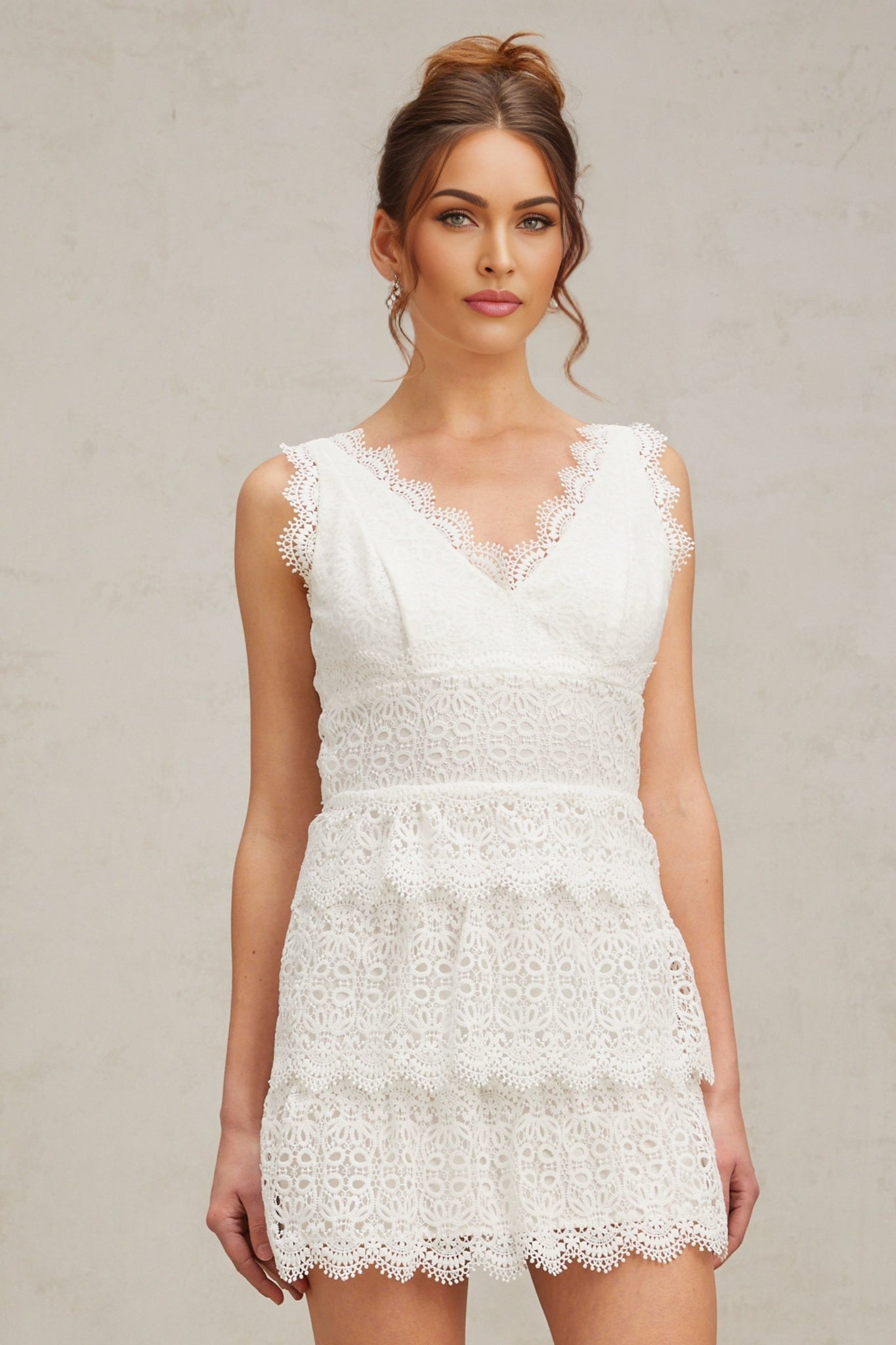 A white mini dress with tiered lace layers and a feminine silhouette