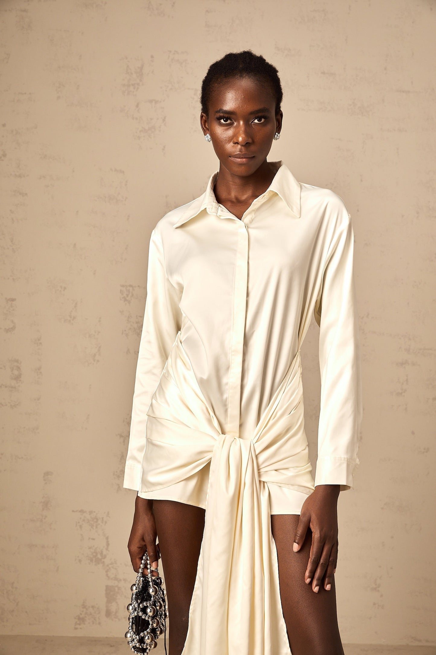 A white mini shirt dress with ruched detailing and ribbon accents named Daphne featuring a short length and buttonup front