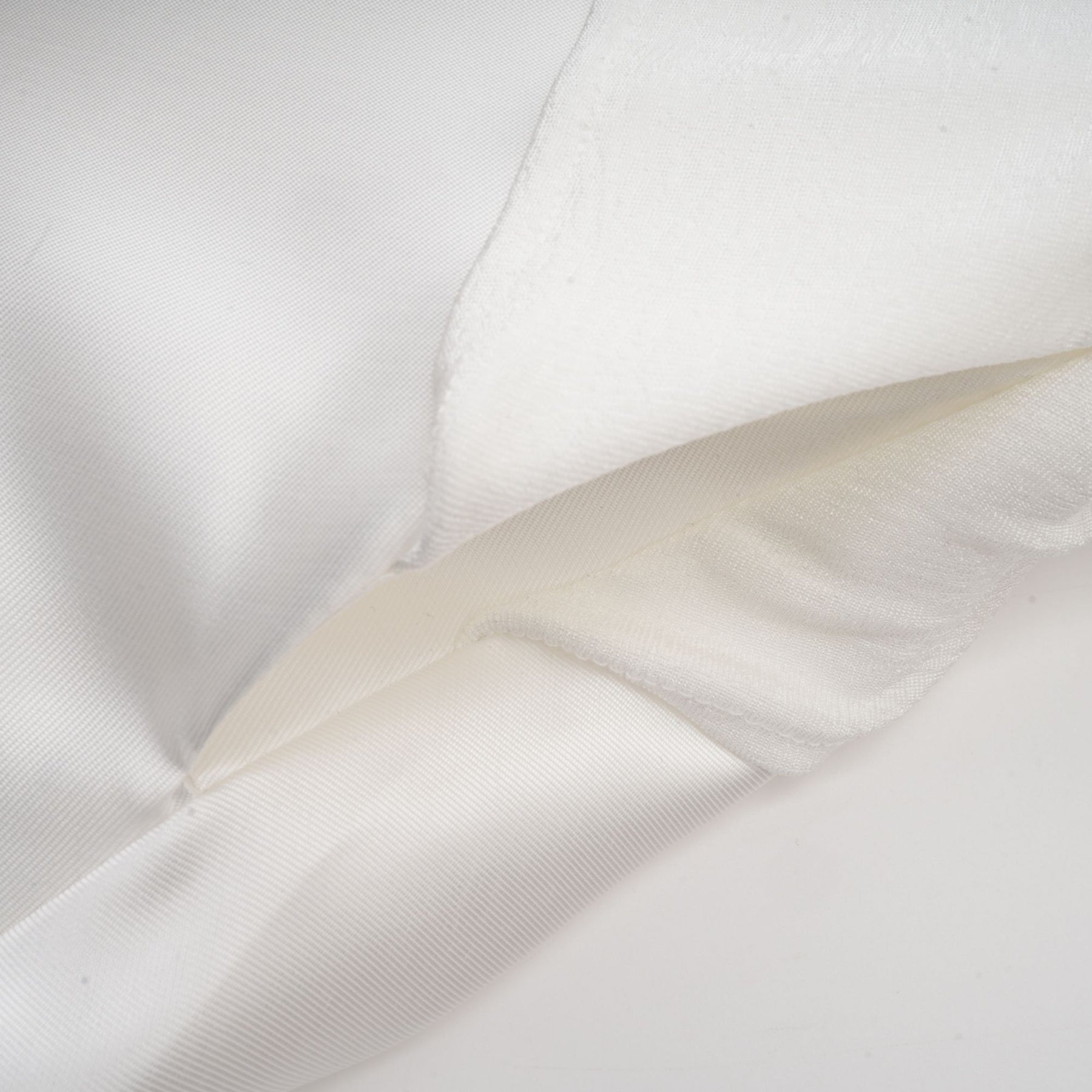 A white offshoulder maxi dress with panel detailing worn by a model standing against a plain background