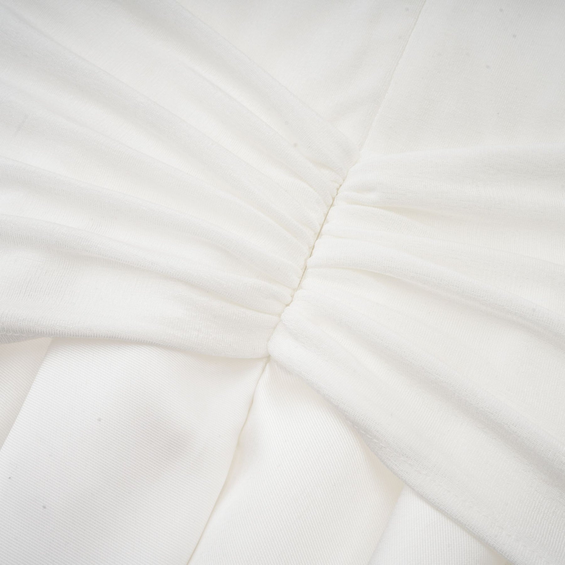 A white offshoulder maxi dress with panelled design worn by a model standing against a plain background