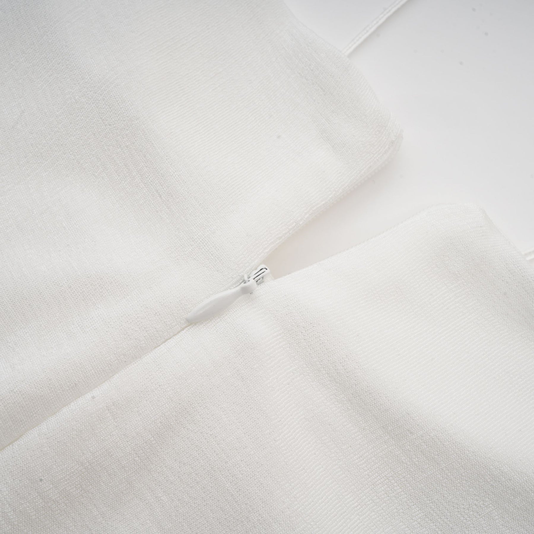 A white offshoulder maxi dress with panelled design worn by a model standing against a plain background