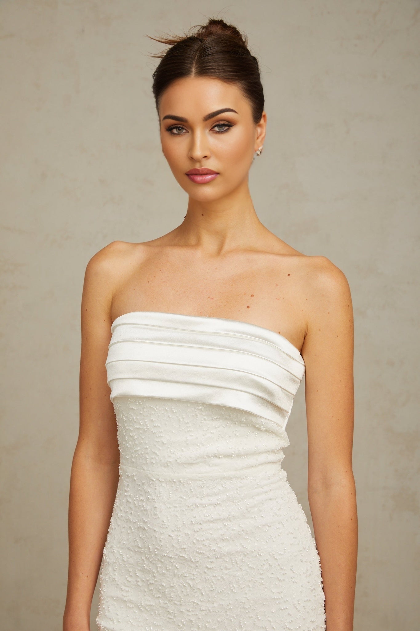 A white offshoulder mini dress with sequin embellishments worn by a model against a plain background