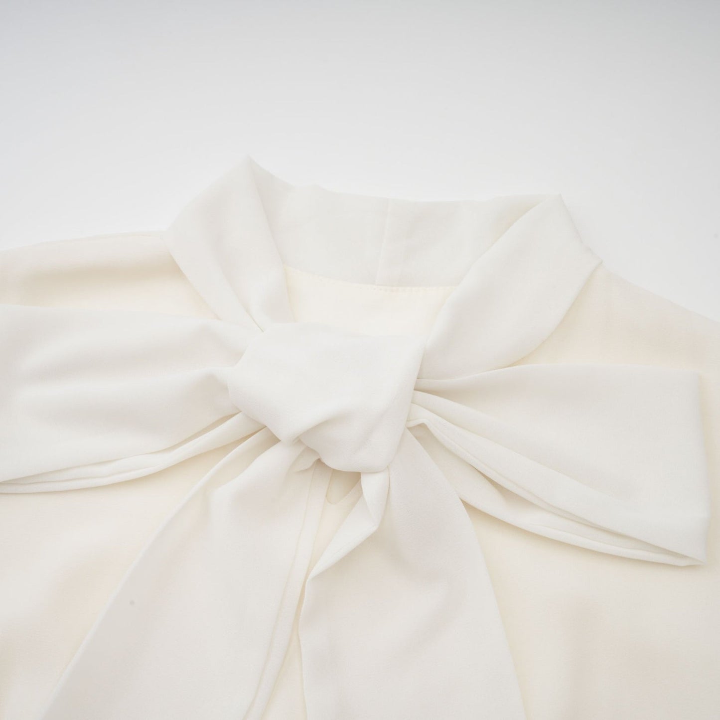 A white pleated jacket and dress set with embellishments featuring a matching design The jacket is worn over the dress creating an elegant coordinated outfit