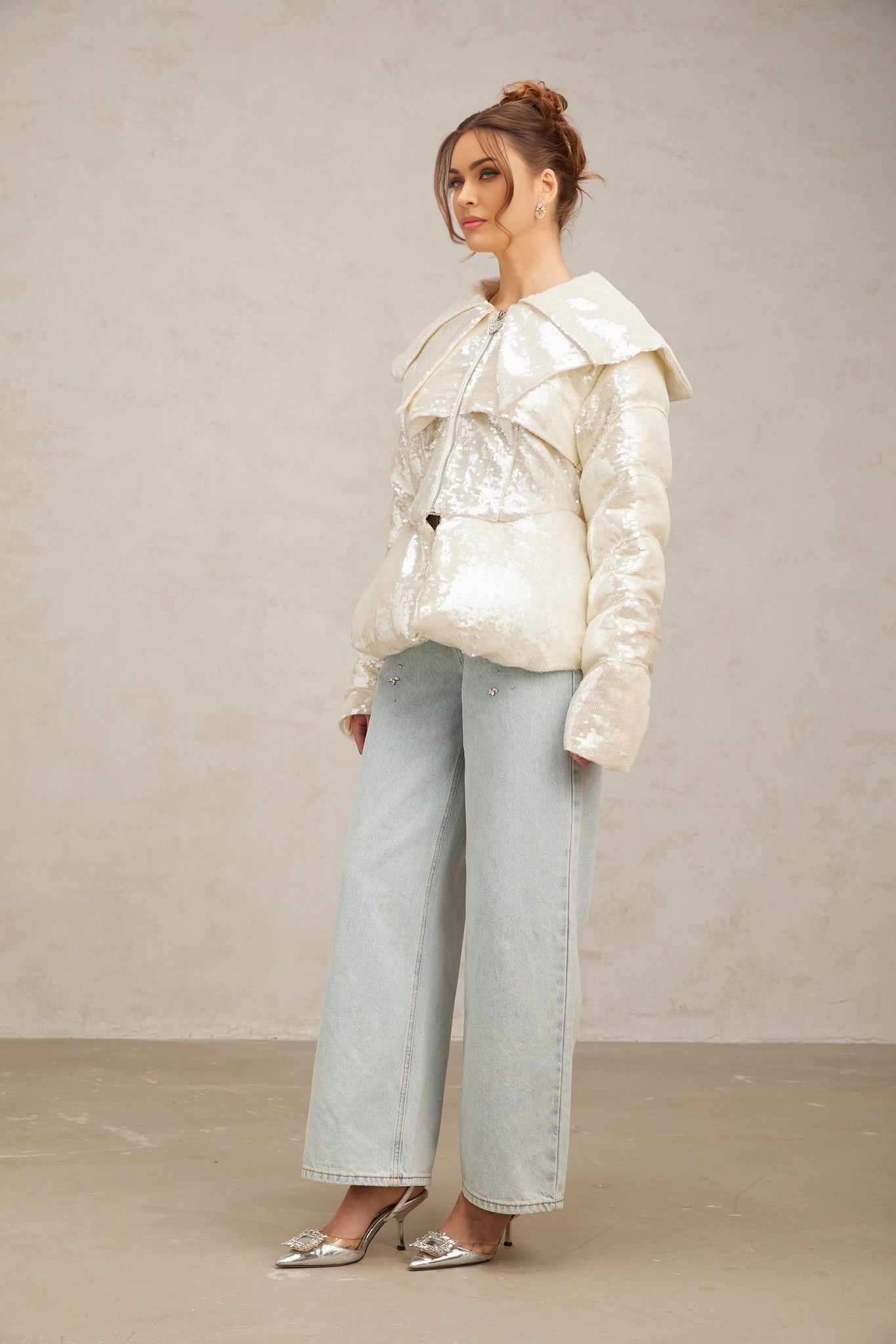 A white puffy down coat adorned with shimmering sequins covering the entire outer surface