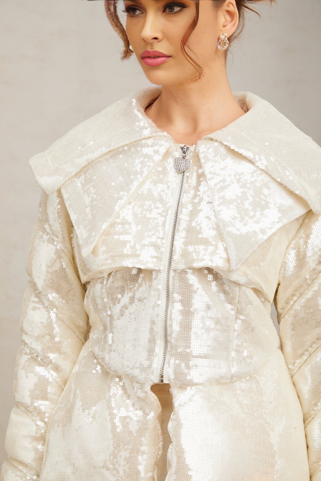 A white puffy down coat adorned with sparkling sequins featuring a feminine design