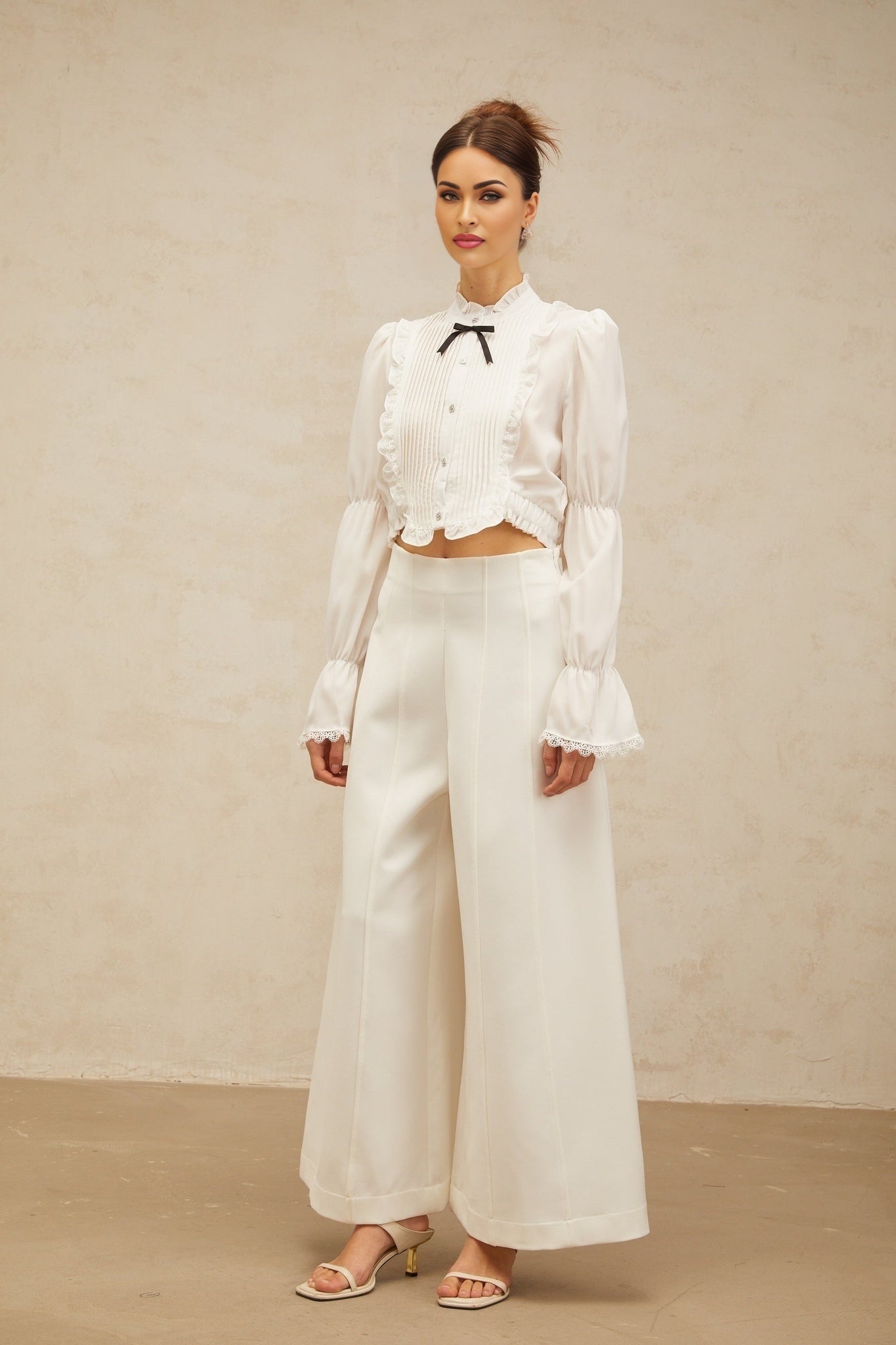 A white ruffled shirt with a bow knot detail and shirred panels featuring a feminine design and delicate texture