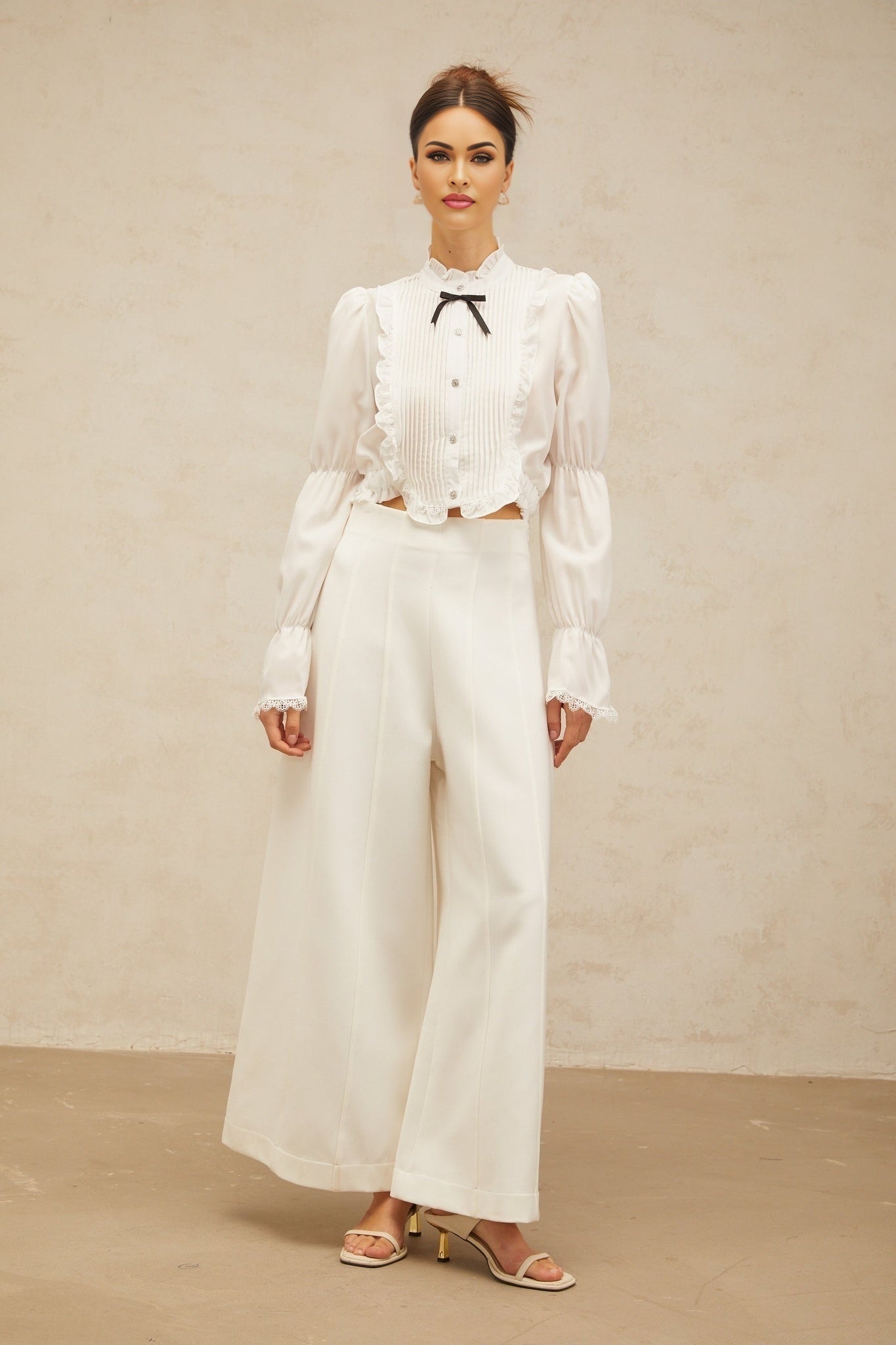 A white ruffled shirt with a bow tie detail and shirred panels featuring a feminine and elegant design