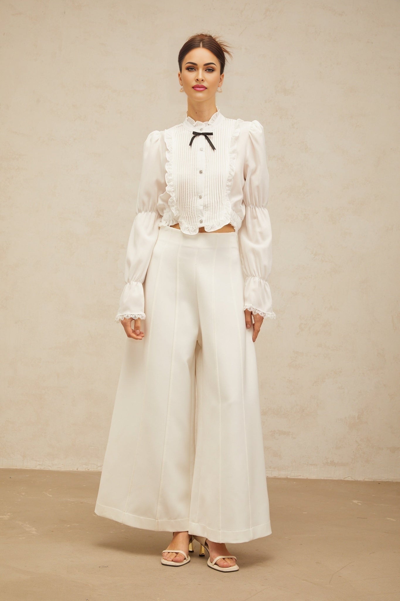 A white ruffled shirt with a bow tie neckline and shirred panels featuring a feminine and elegant design
