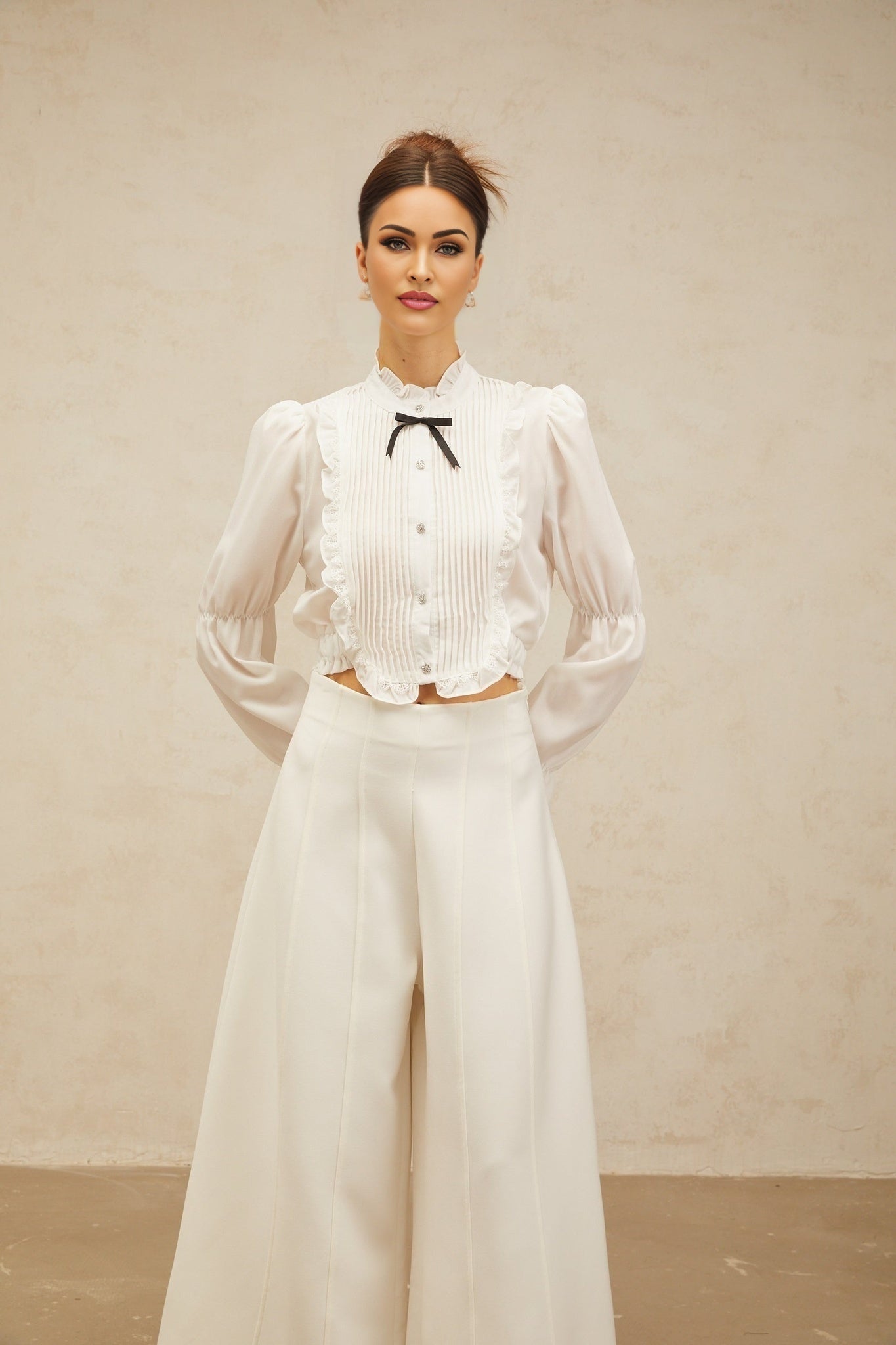 A white ruffled shirt with a bowknot detail and shirred panel featuring a feminine and elegant design
