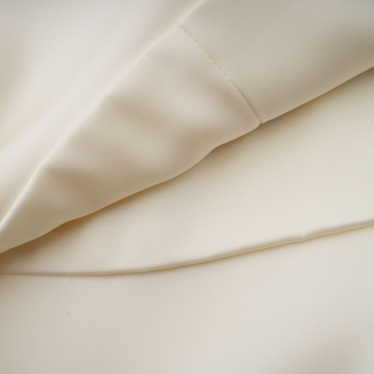 A white satin mini dress with ruffled details and a shawl panel accent shown on a model against a plain background