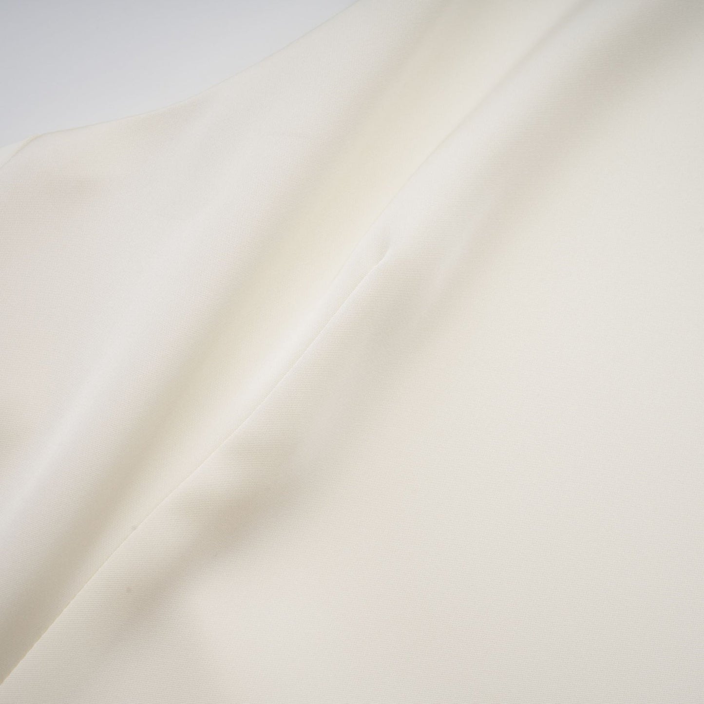 A white satin mini dress with ruffled details and a shawl panel feature worn by a model standing against a plain background