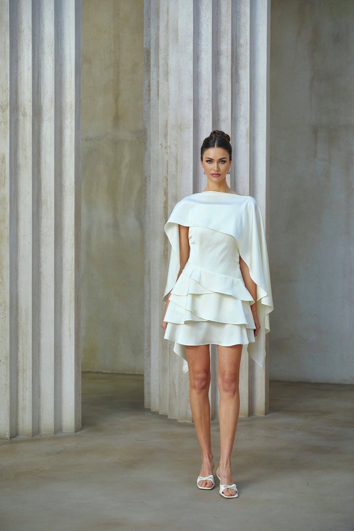 A white satin mini dress with ruffled details and a shawl panel featuring a sleek silhouette and feminine design