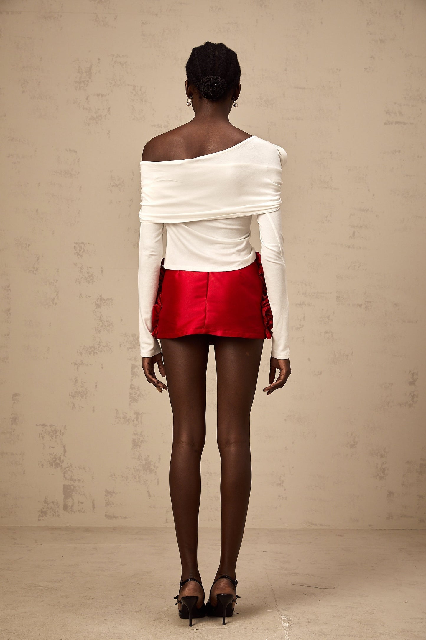 A white sleeveless jersey top with an asymmetric design featuring a twisted detail on one side