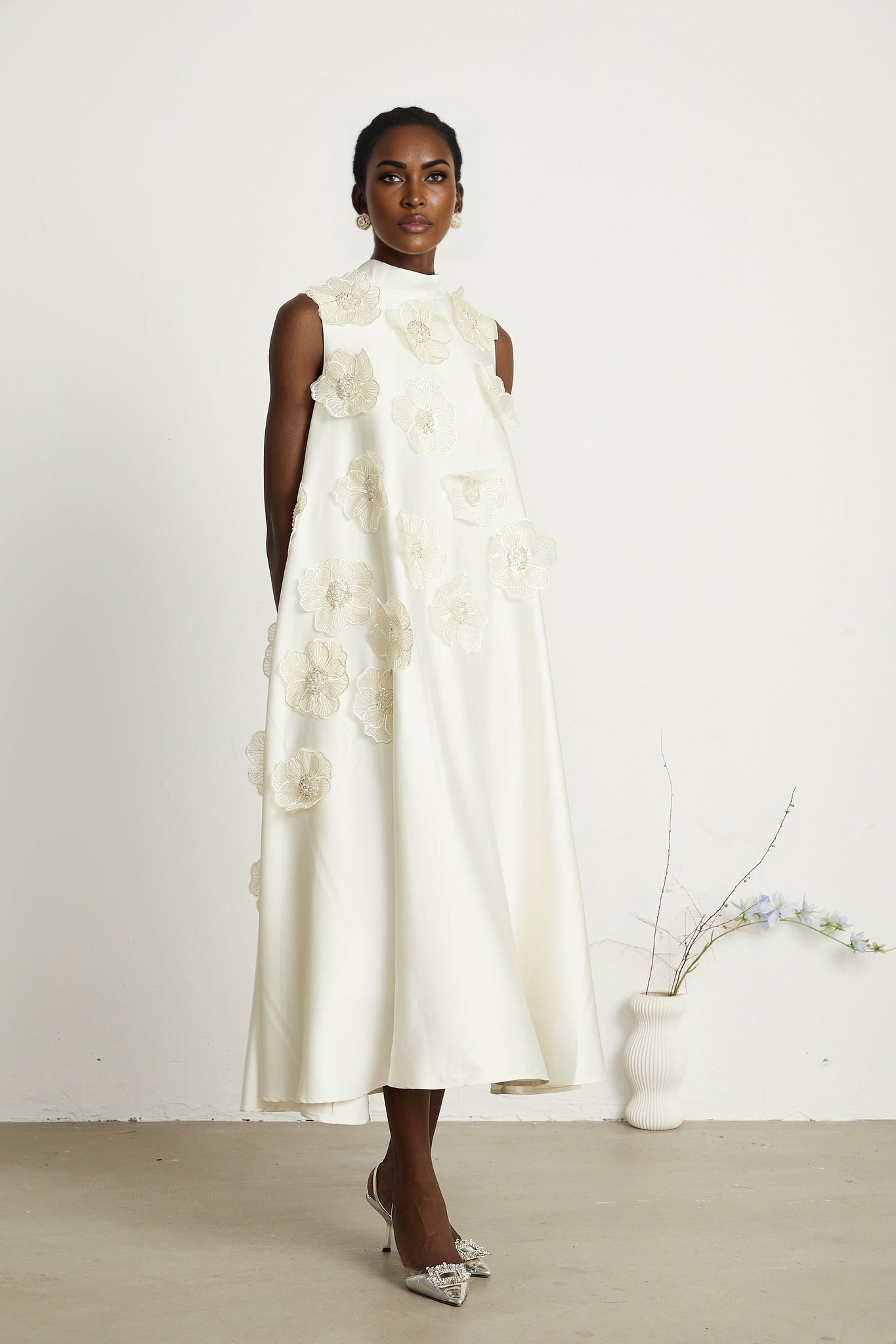 A white sleeveless midi dress with floral applique detailing named Emilie