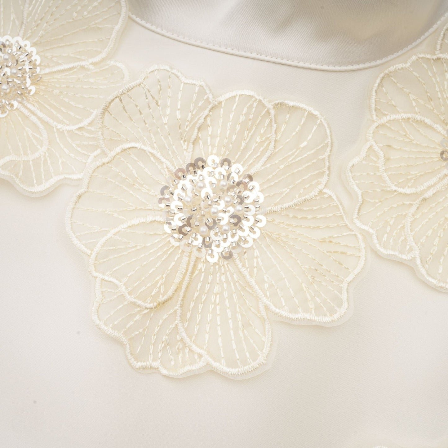 A white sleeveless midi dress with floral applique details called the Emilie dress