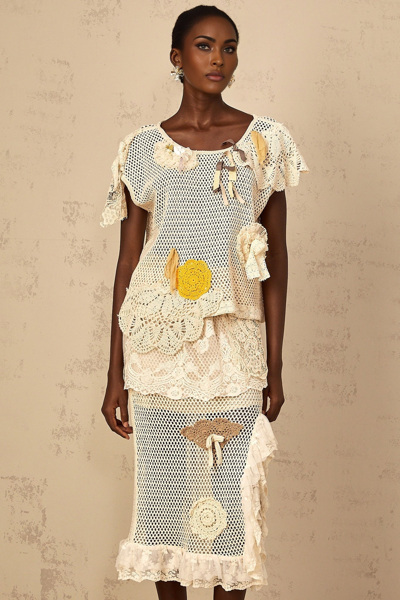 A white sleeveless top with a lace panel on the front and crochet knit pattern throughout