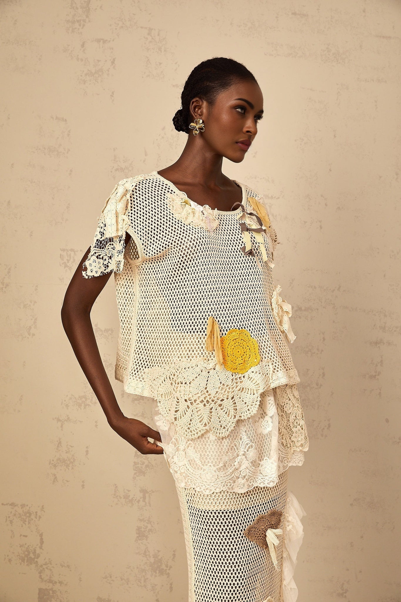 A white sleeveless top with intricate lace panels and crochet knit detailing featuring a scoop neckline and delicate feminine design