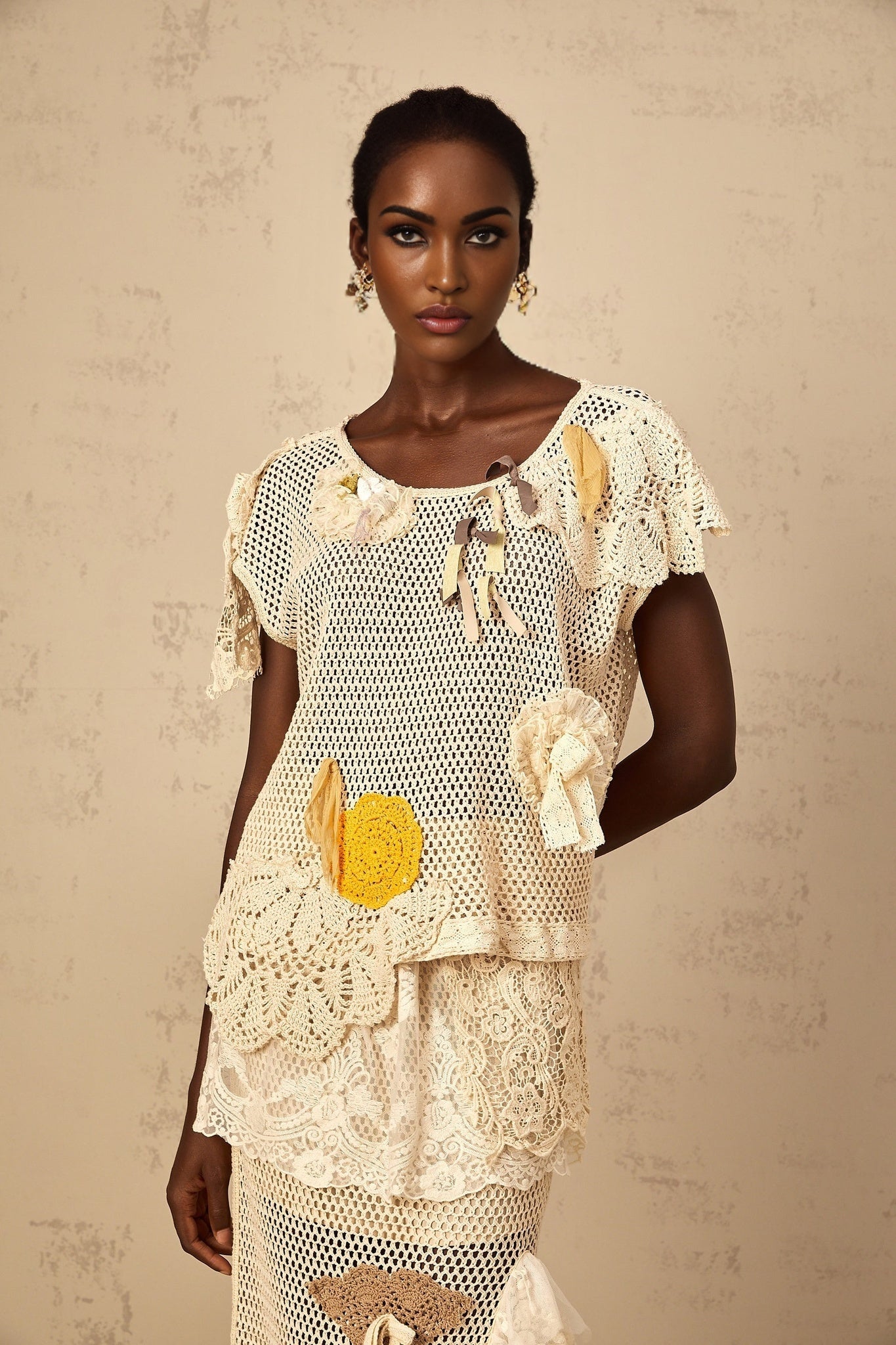 A white sleeveless top with lace panels and crochet knit pattern