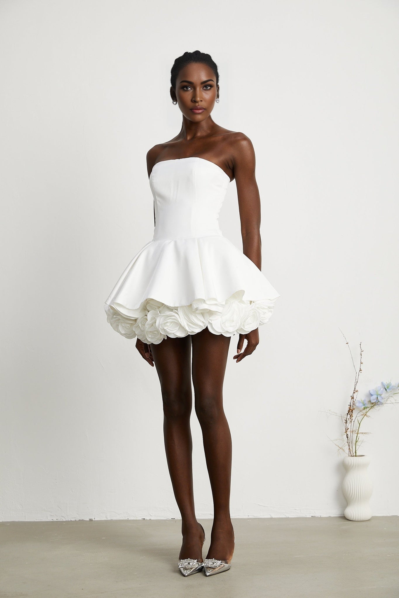 A white strapless mini dress with a corsetstyle bodice adorned with floral petal details called Lucie
