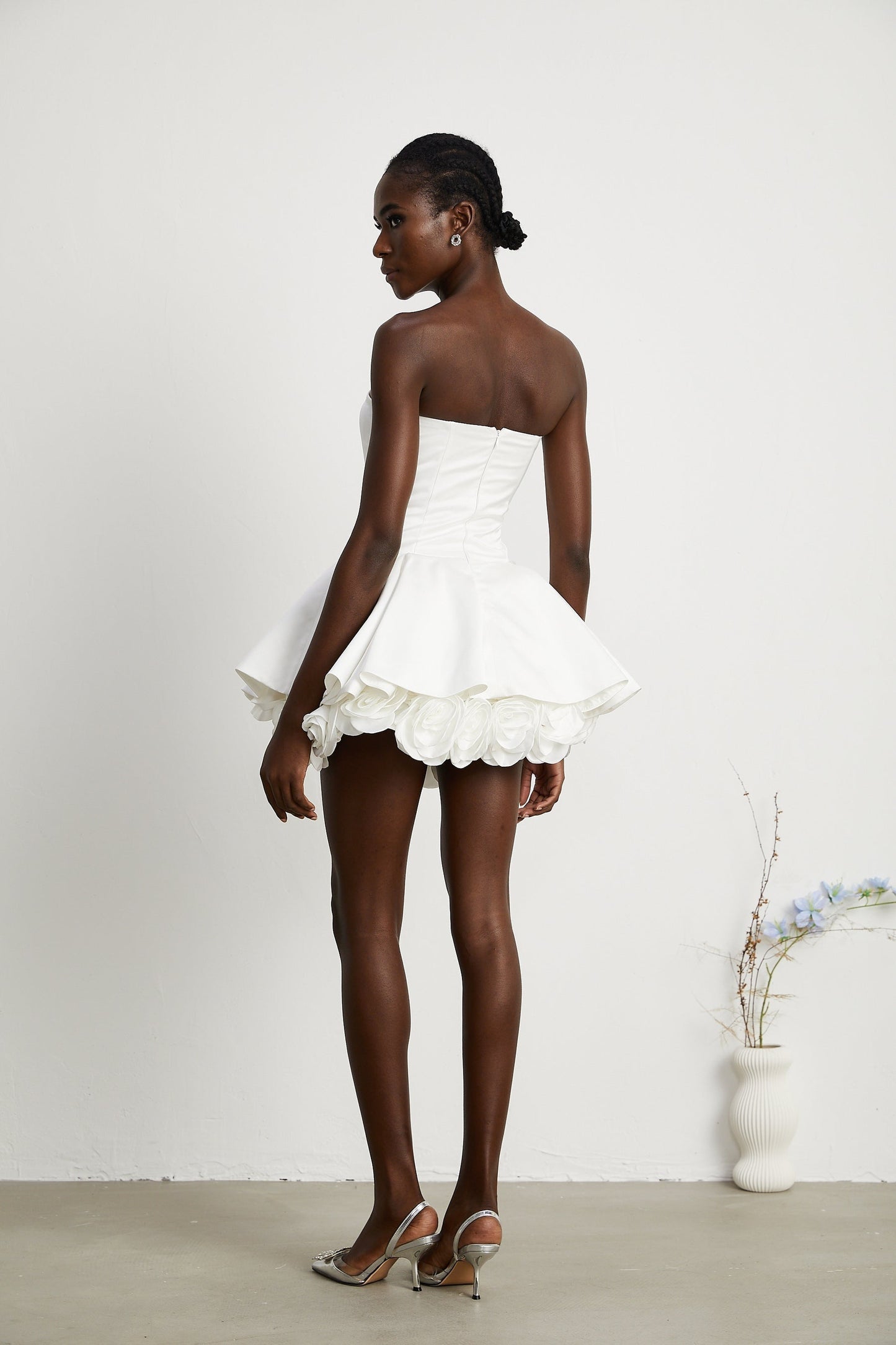 A white strapless mini dress with a corsetstyle bodice adorned with floral petal details named Lucie