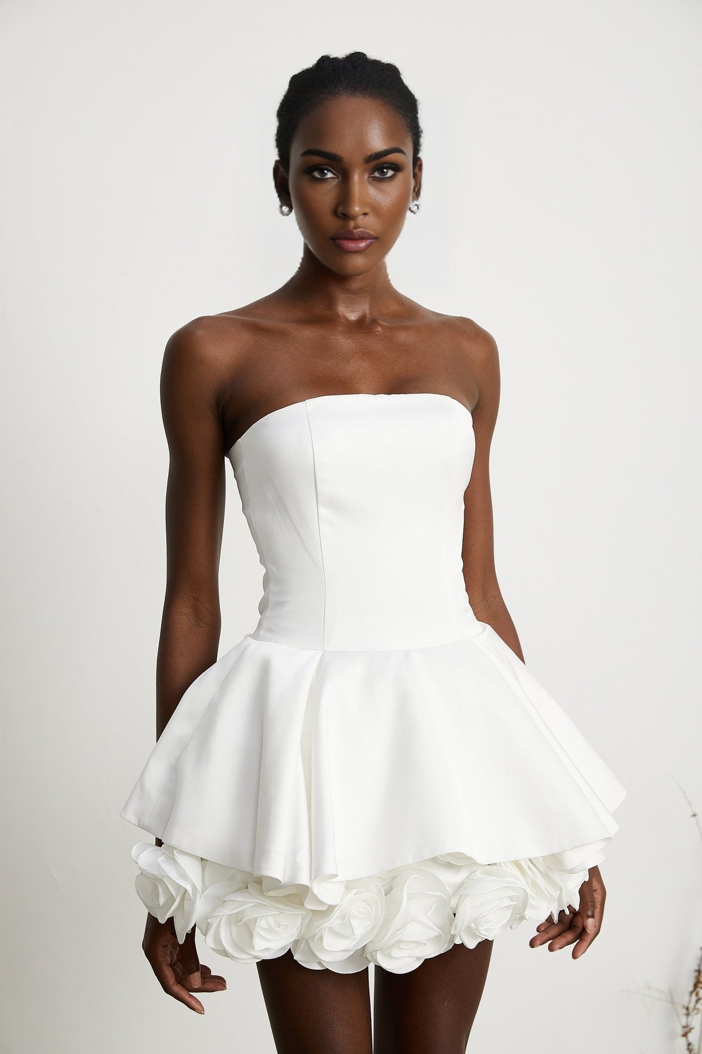 A white strapless mini dress with a corsetstyle bodice adorned with floral petal details named Lucie