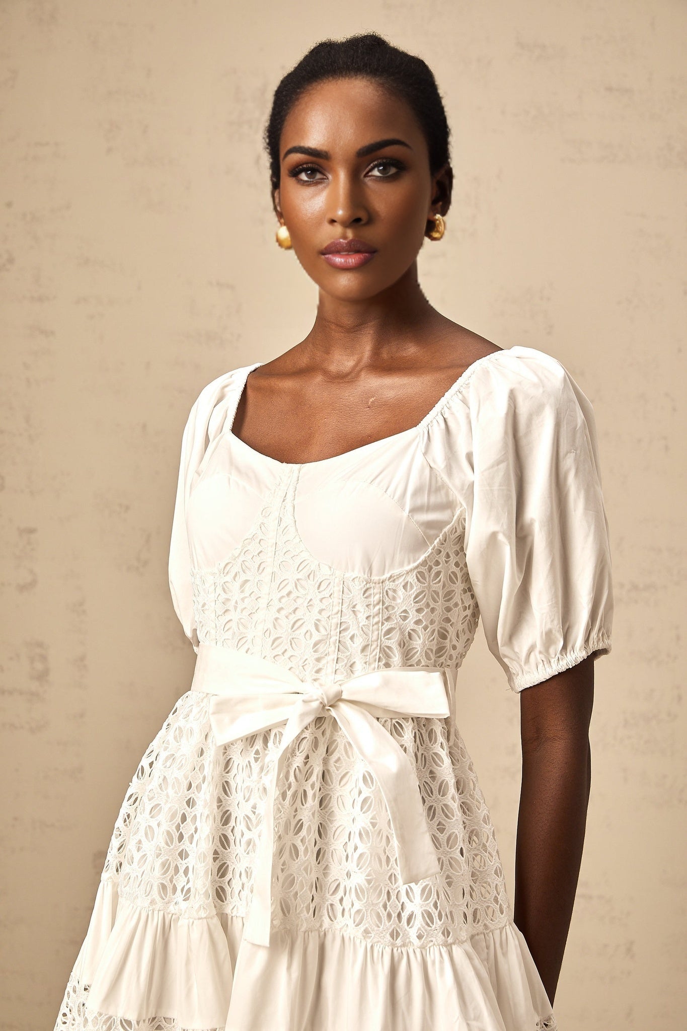 A white tiered midi dress made of corded lace featuring a feminine and elegant design with multiple layers