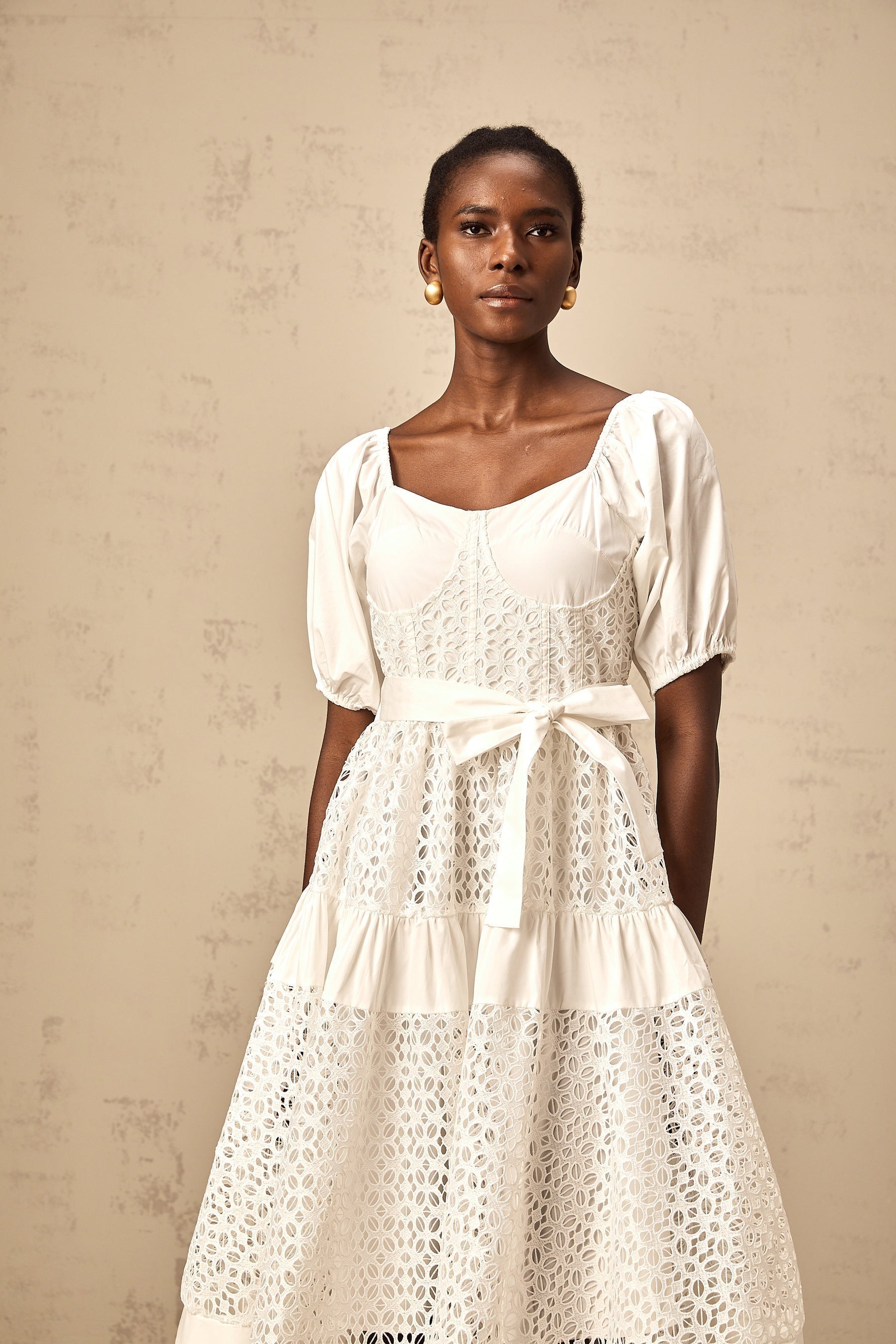 A white tiered midi dress made of corded lace named Helene featuring a delicate feminine design with multiple layers