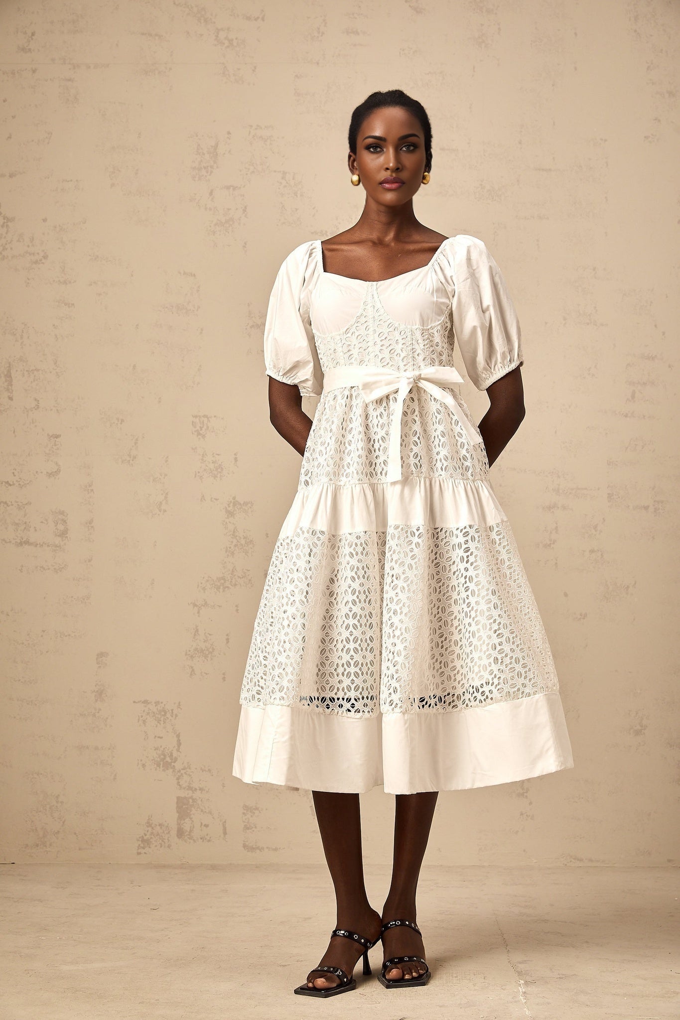A white tiered midi dress made of corded lace with a feminine and elegant design