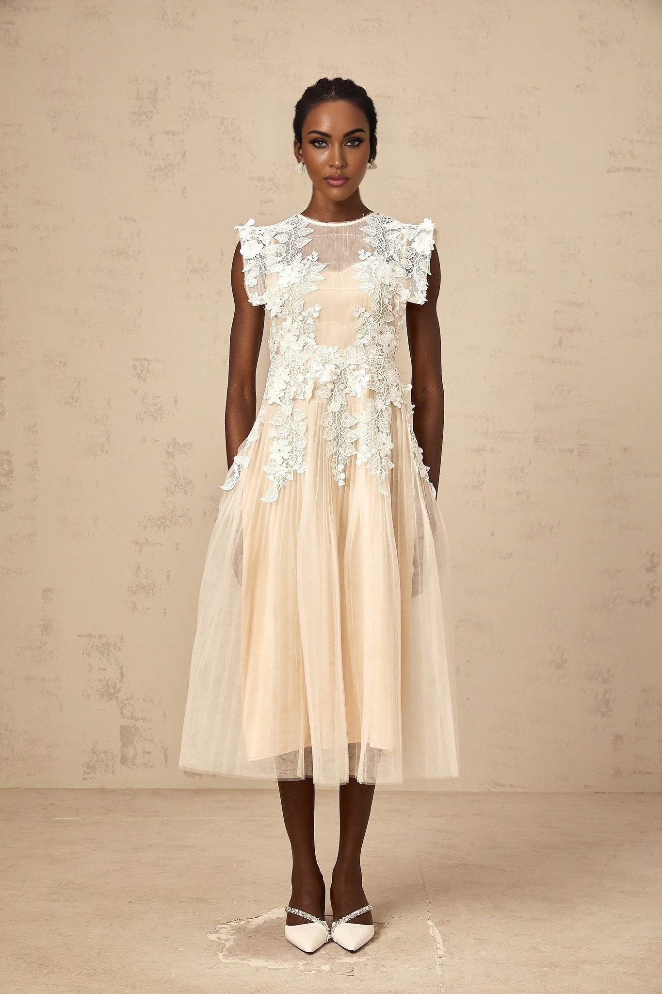 A white tulle midi dress with delicate flower appliques scattered across the bodice and skirt featuring a fitted waist and flowing silhouette
