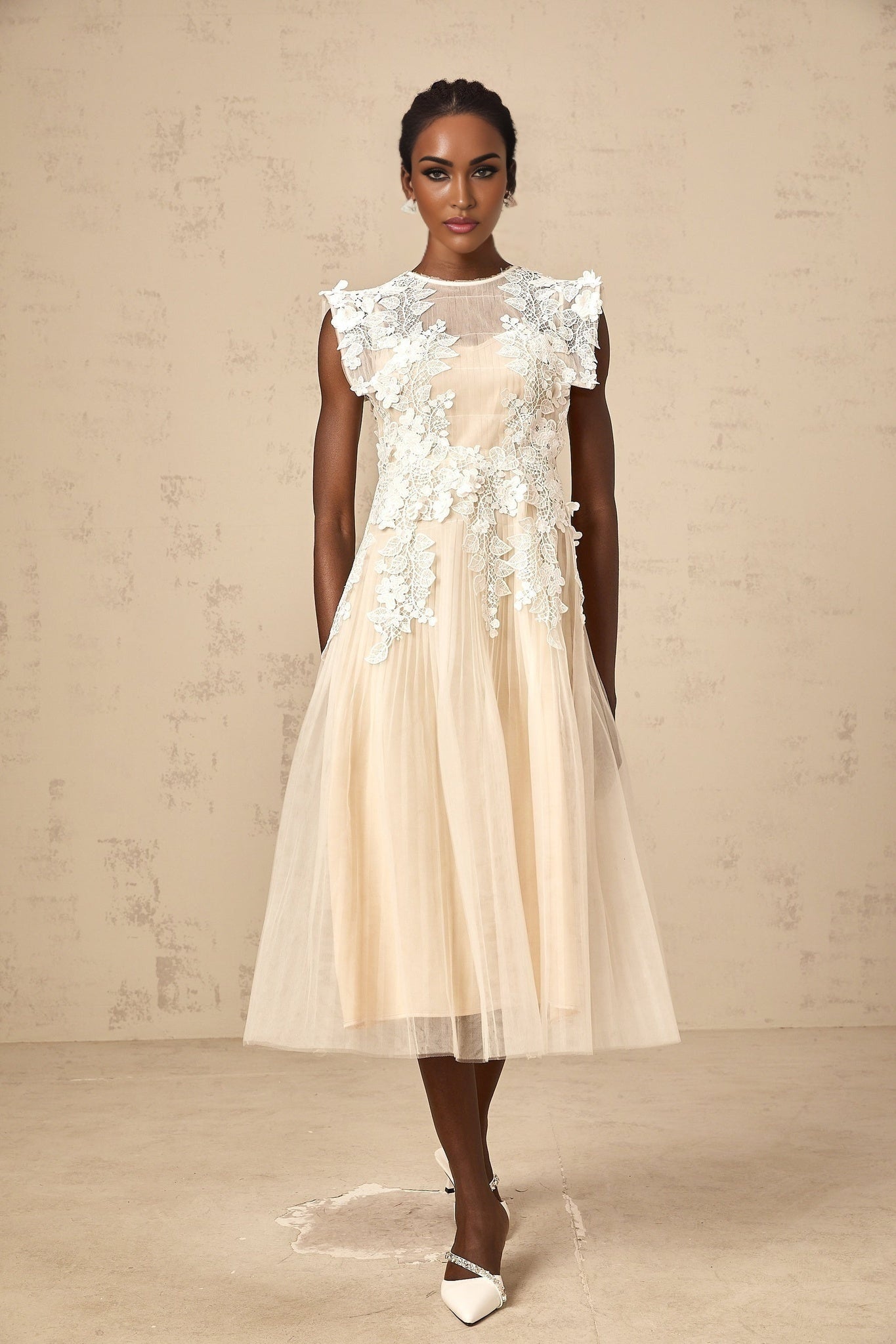 A white tulle midi dress with floral appliques scattered across the bodice and skirt featuring a fitted waist and flowing silhouette