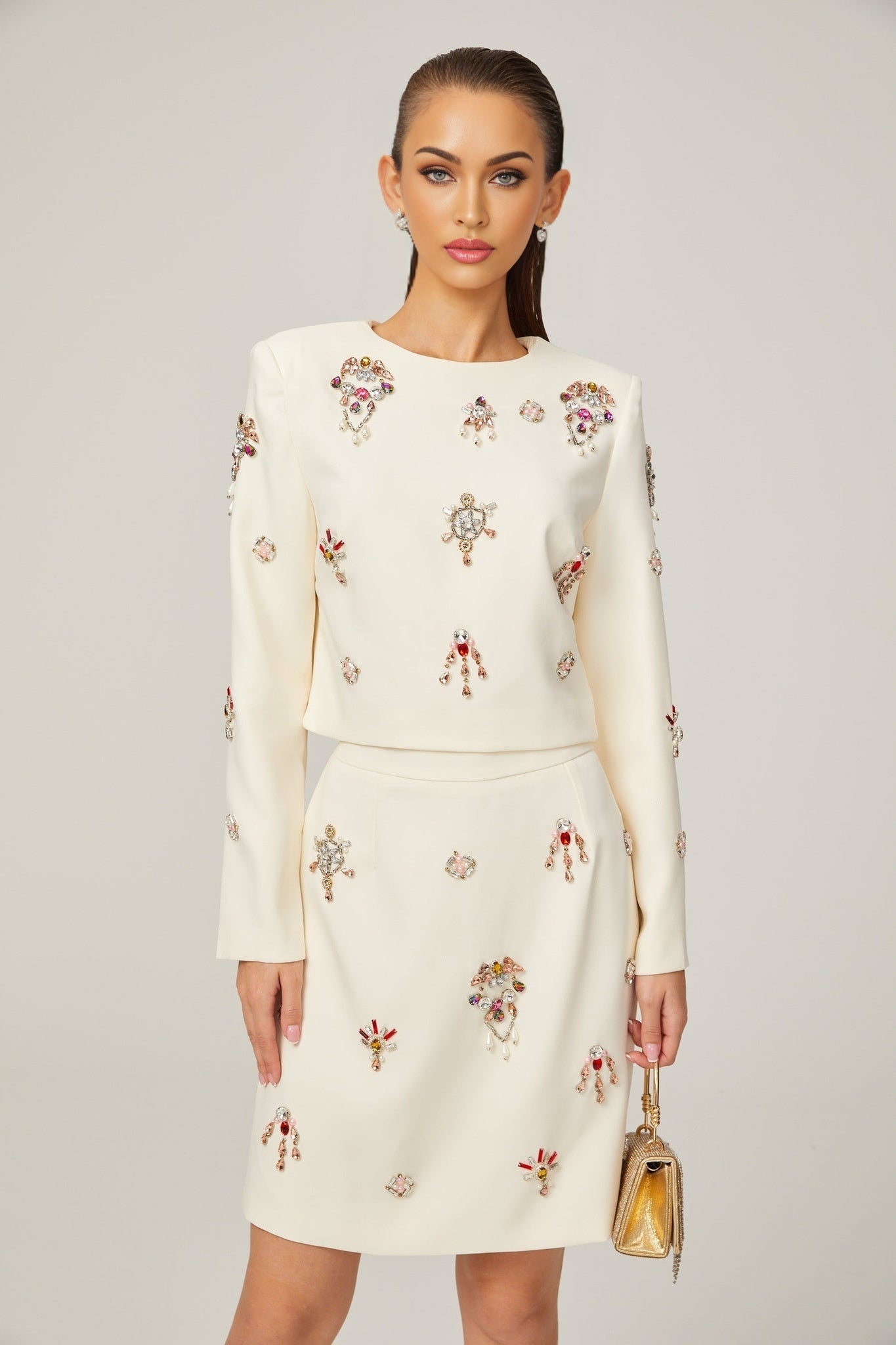 A white twopiece outfit consisting of a top and skirt adorned with crystal embellishments The set features a matching design with sparkling details throughout
