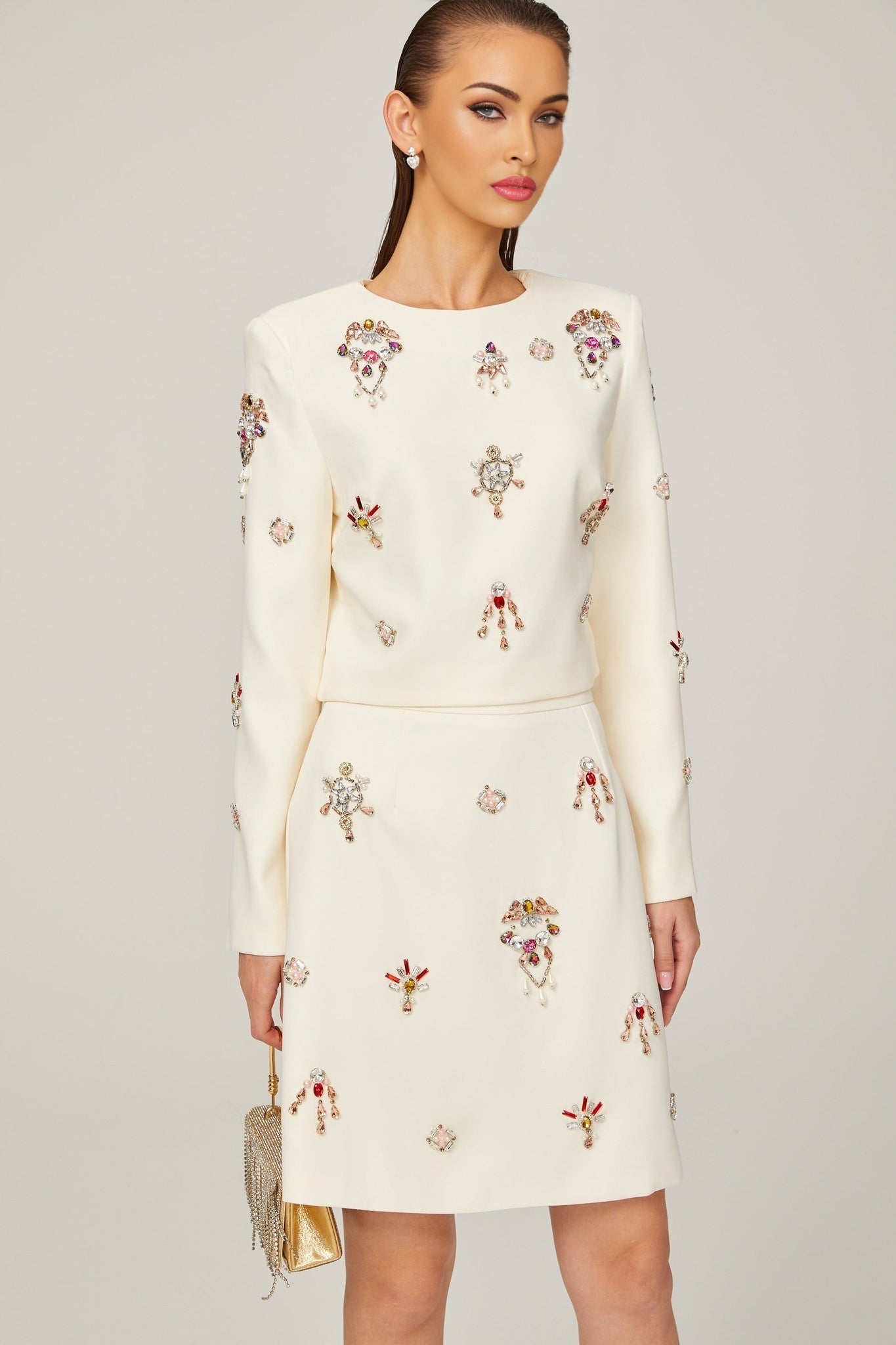 A white twopiece outfit consisting of a top and skirt adorned with crystal embellishments The set features a matching design with sparkling details throughout