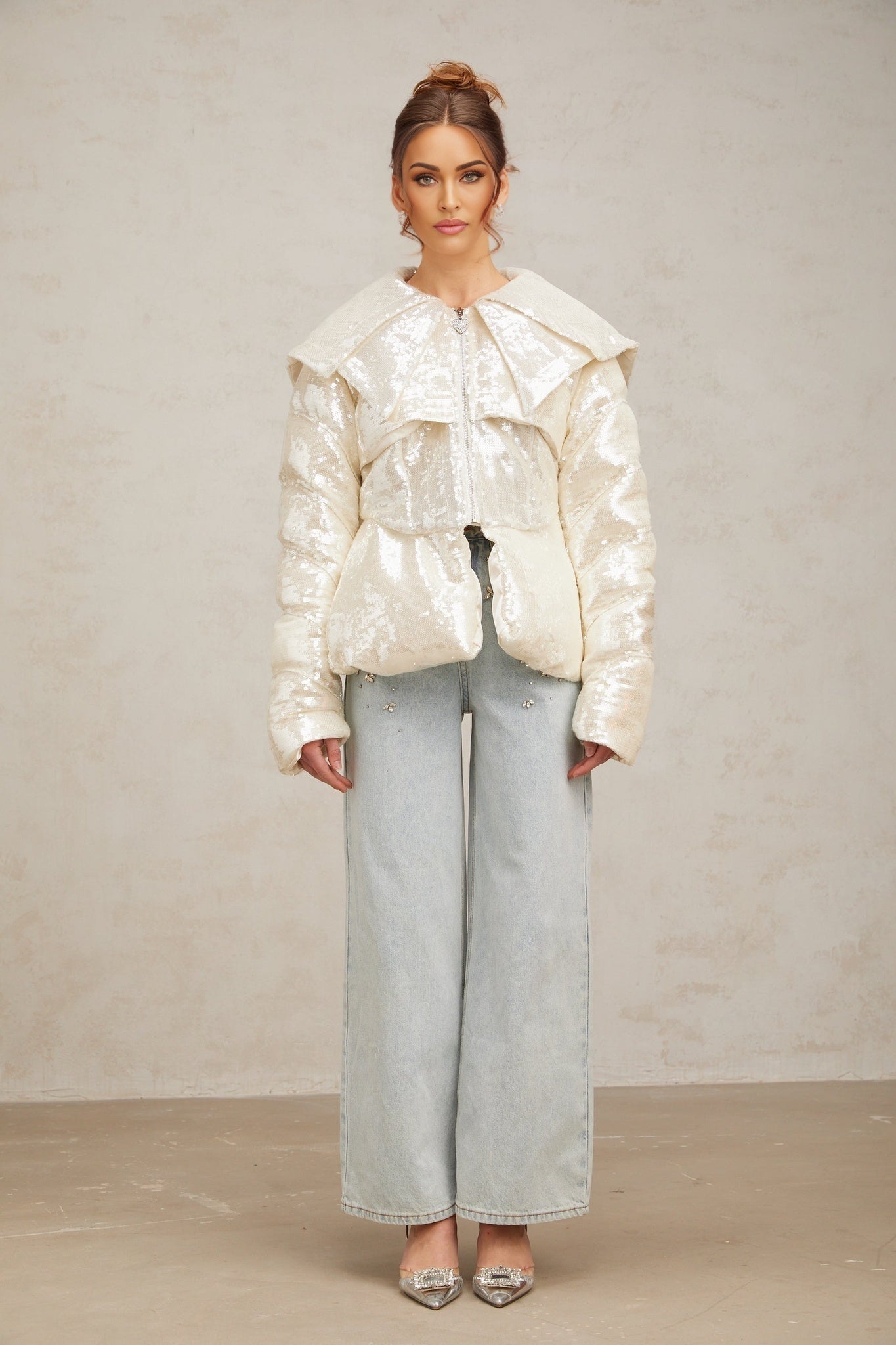 A white winter coat with sequin embellishments and down insulation featuring a woman named Joslyn wearing the garment