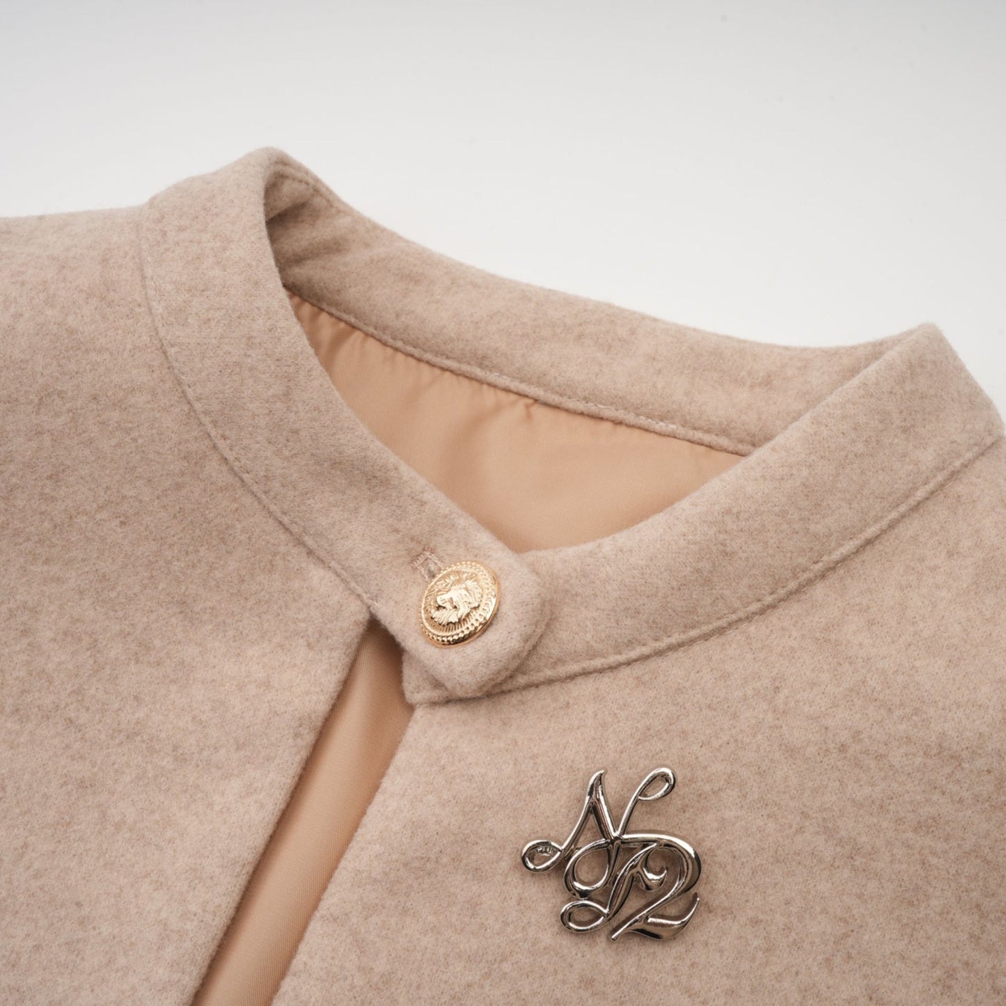 A winter coat with a detachable cape made of black faux fur featuring a high collar and long sleeves