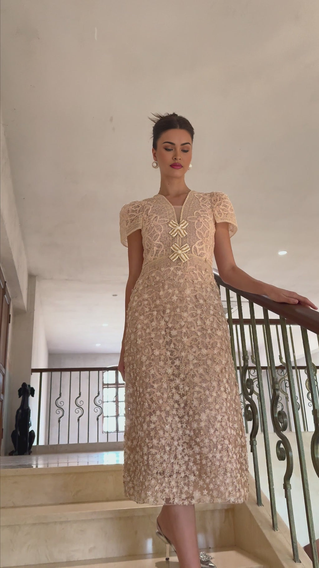 A woman wearing a beige crochet midi dress with faux flower details standing in a neutral background