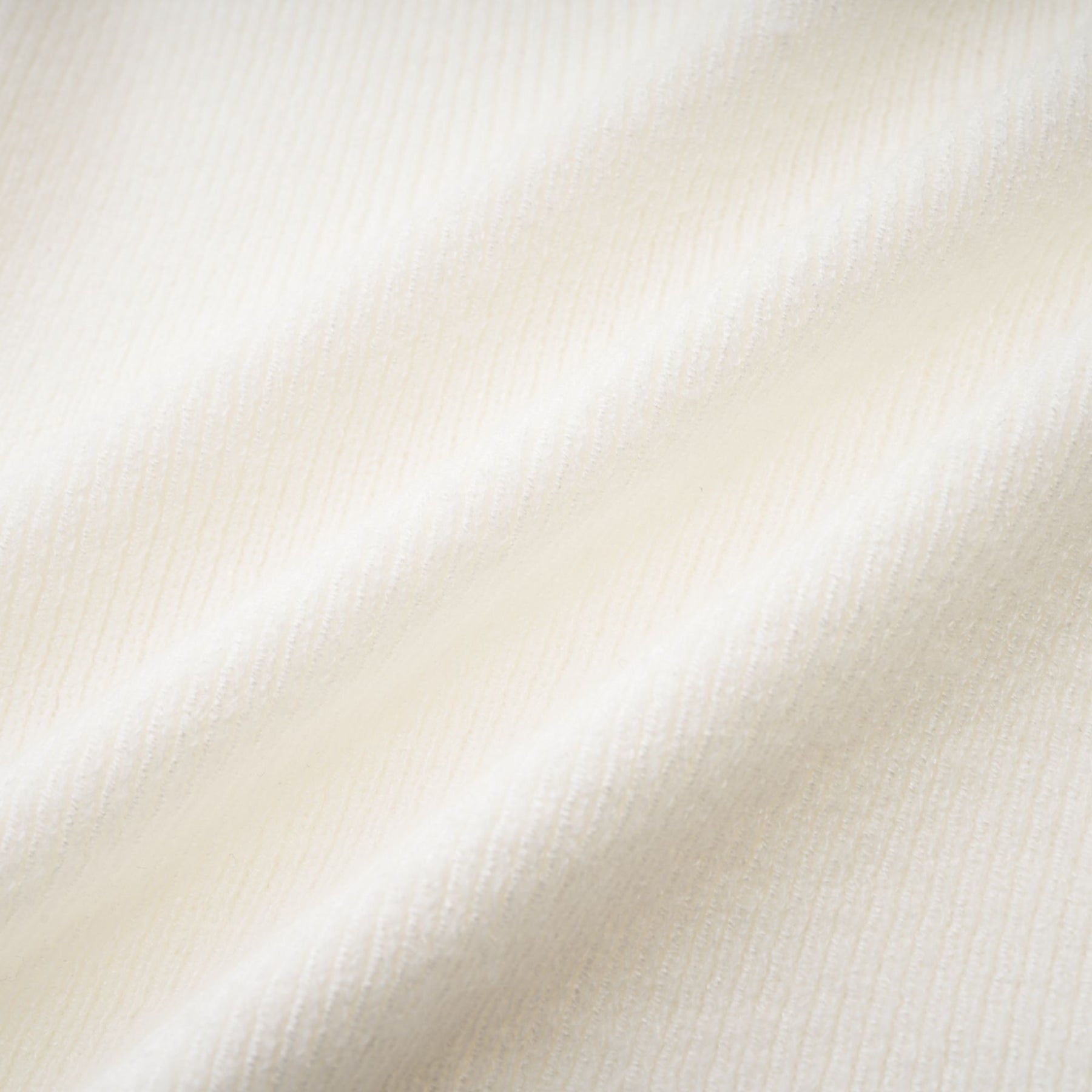 A woman wearing a beige knit long sleeve top with offshoulder design