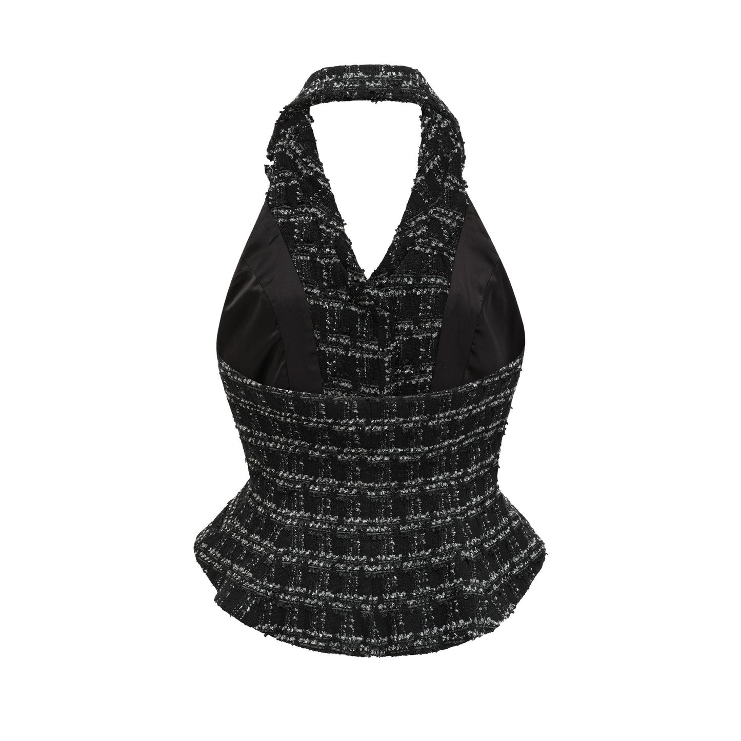 A woman wearing a black and white checked tweed matching set consisting of a sleeveless vest top and a skirt standing against a plain background