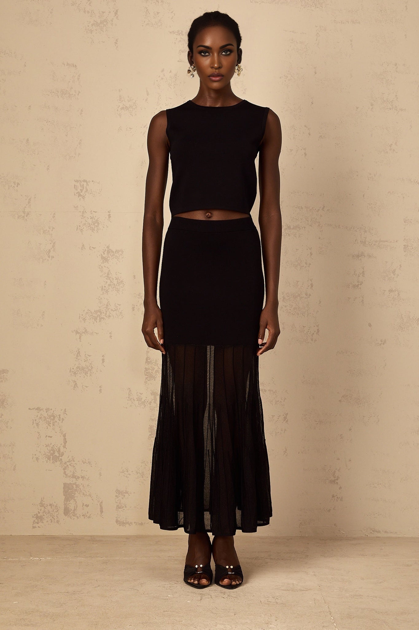 A woman wearing a black fine knit matching set consisting of a long sleeve top and fitted pants with panelled details