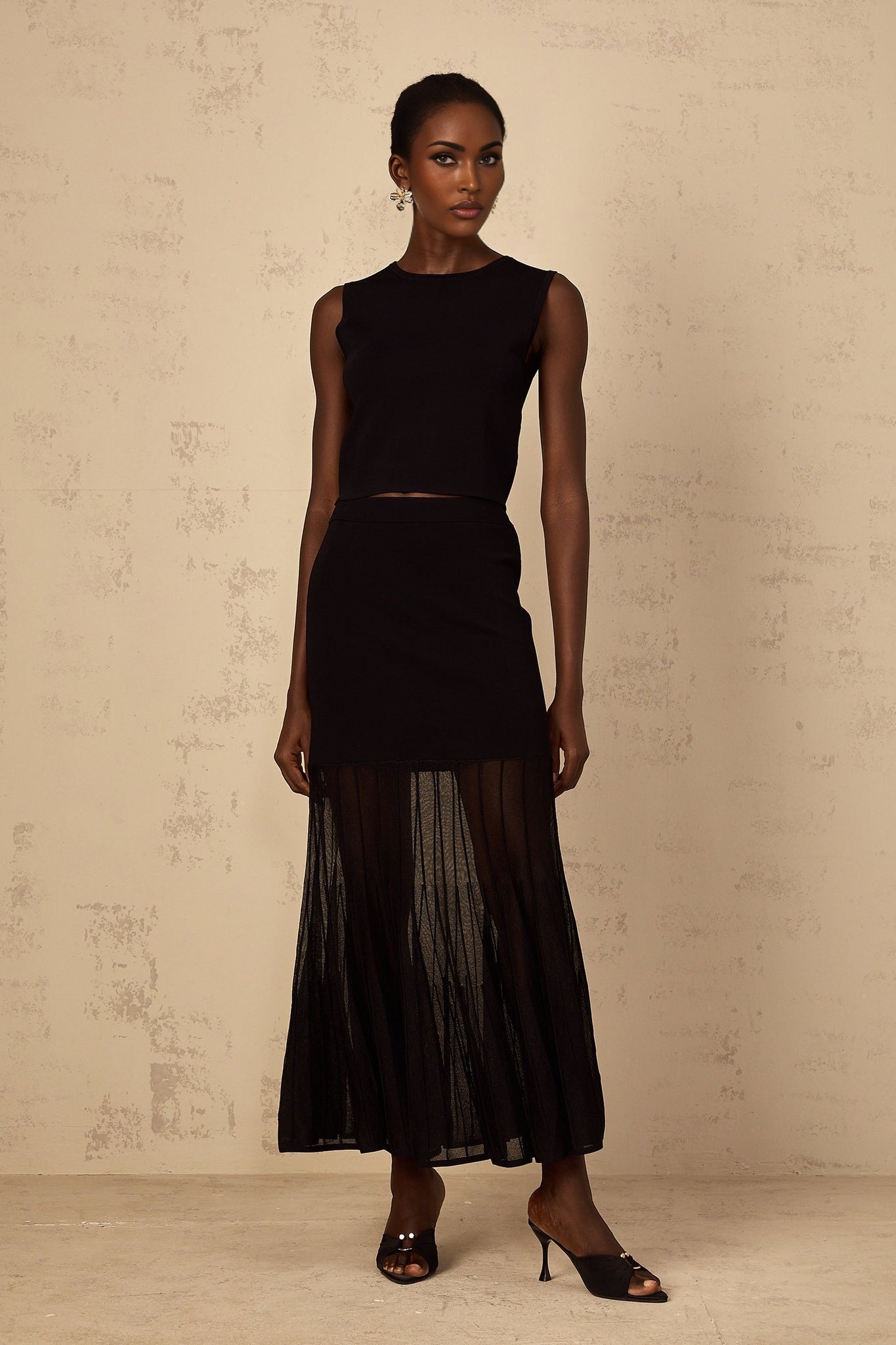 A woman wearing a black fine knit matching set consisting of a top and bottoms with panelled detailing