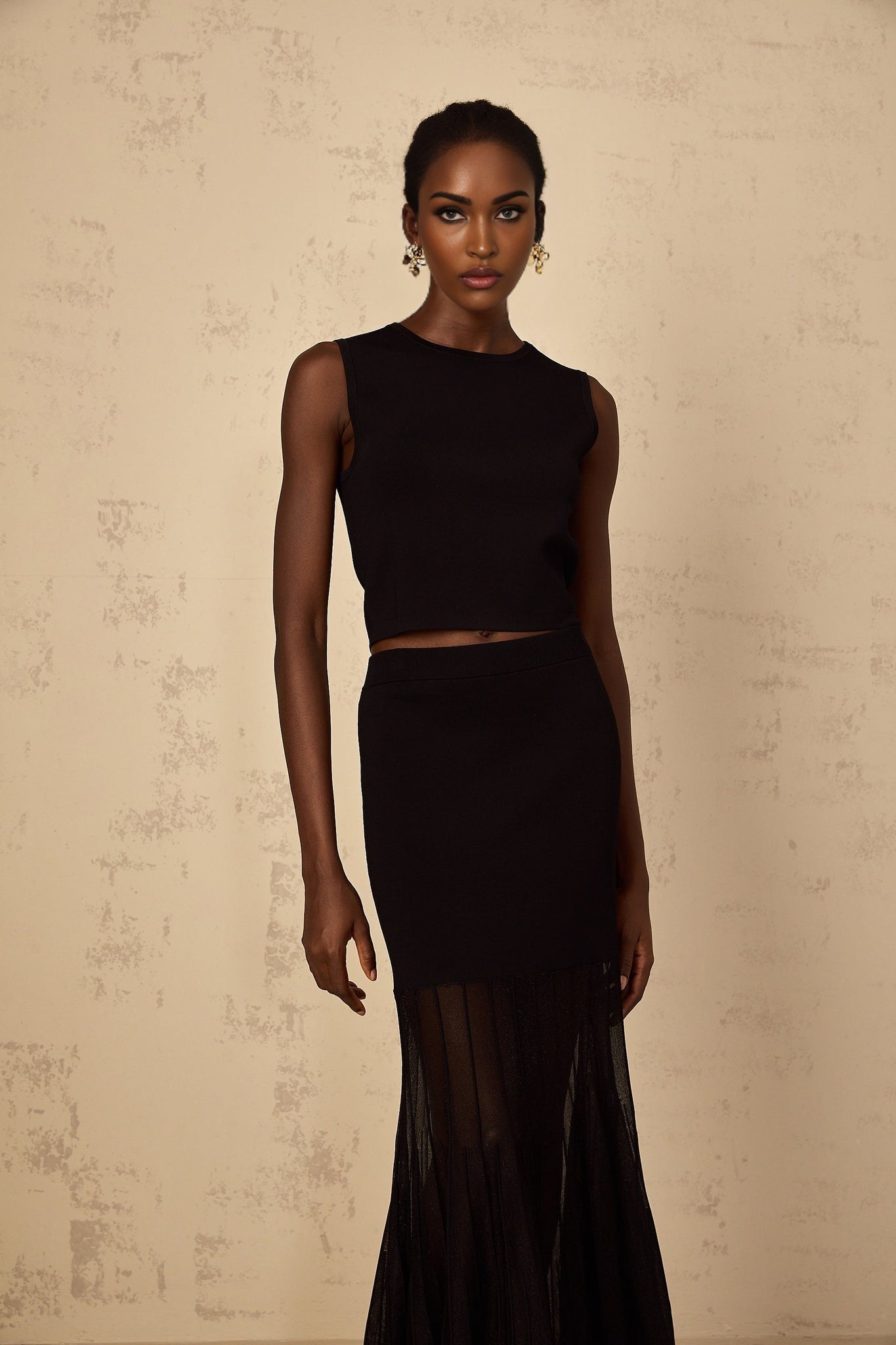 A woman wearing a black fine knit matching set consisting of a top and pants with panelled details